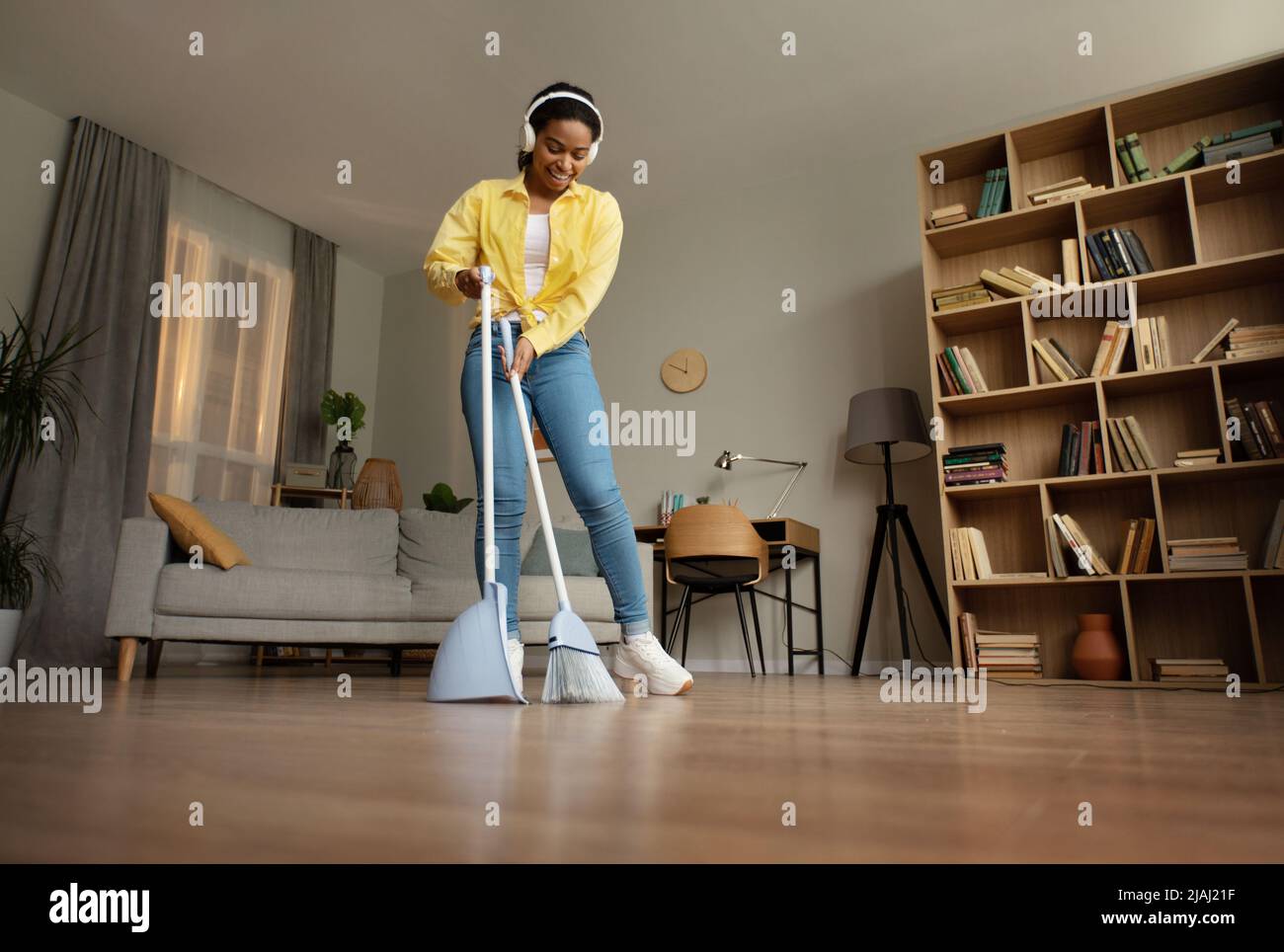 Happy Black Woman Sweeping Floor With Broom Cleaning Home Stock Photo