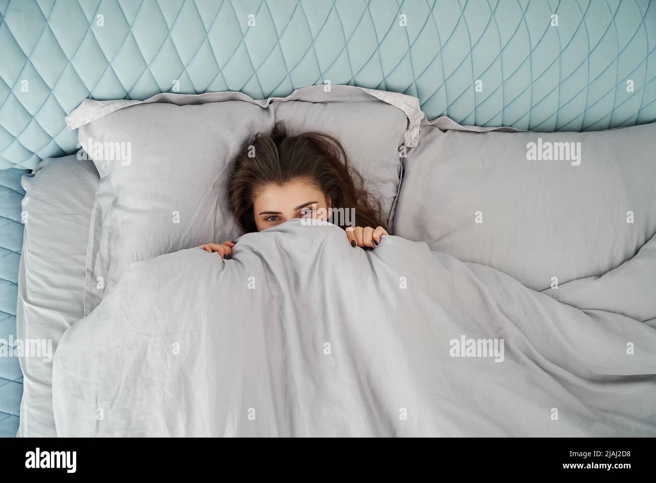 Beautiful woman awake in comfort bed. Rest, bed linen. Apartment. Home lifestyle Stock Photo