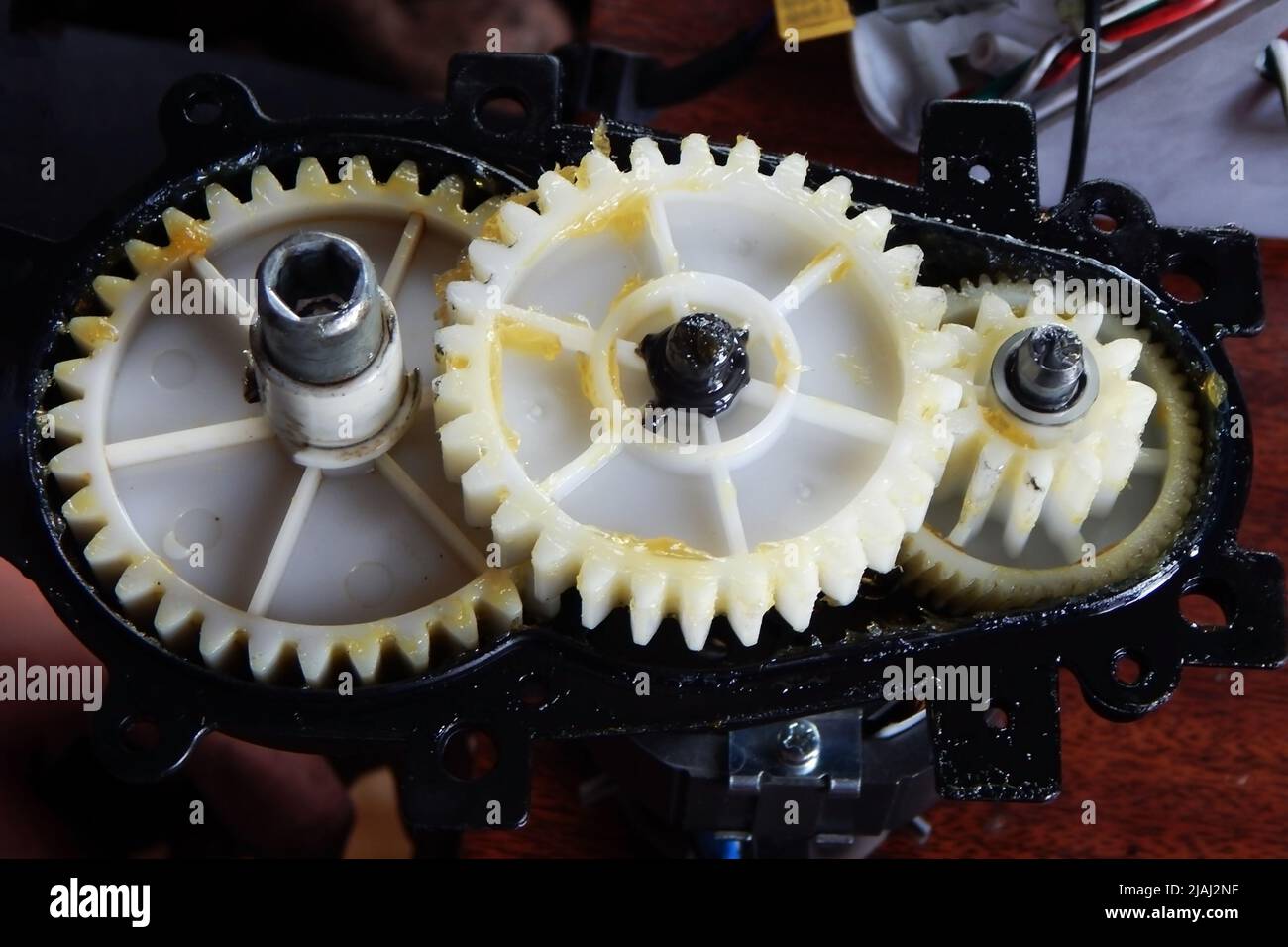 Plastic white gears of the mechanism in yellow grease Stock Photo Alamy