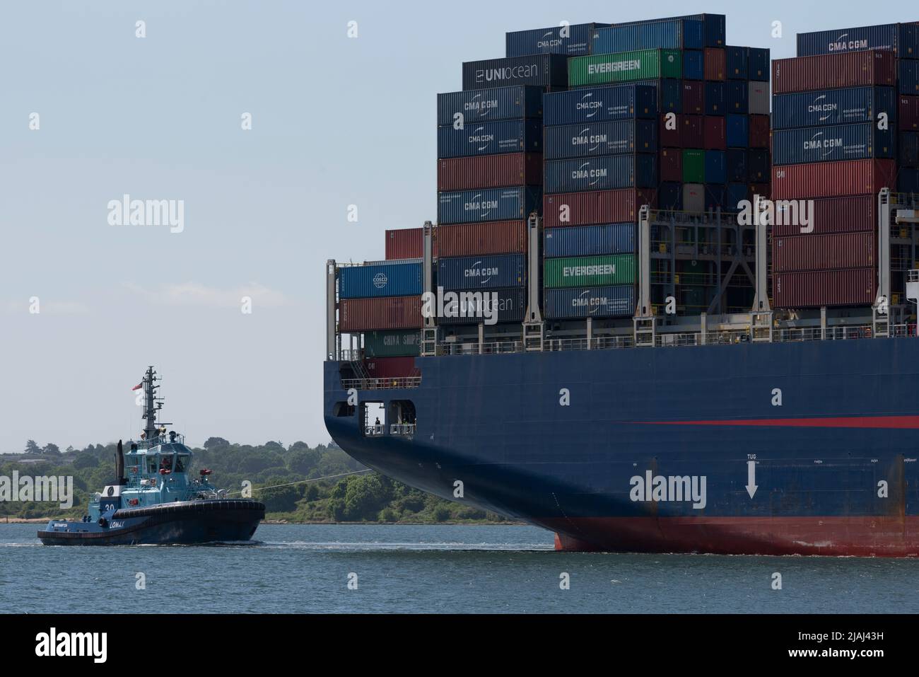 Southampton Water, England, UK. 2022.  Large container ship inbound to DP World Southampton container port with a blue ccoloured tug escort. Stock Photo