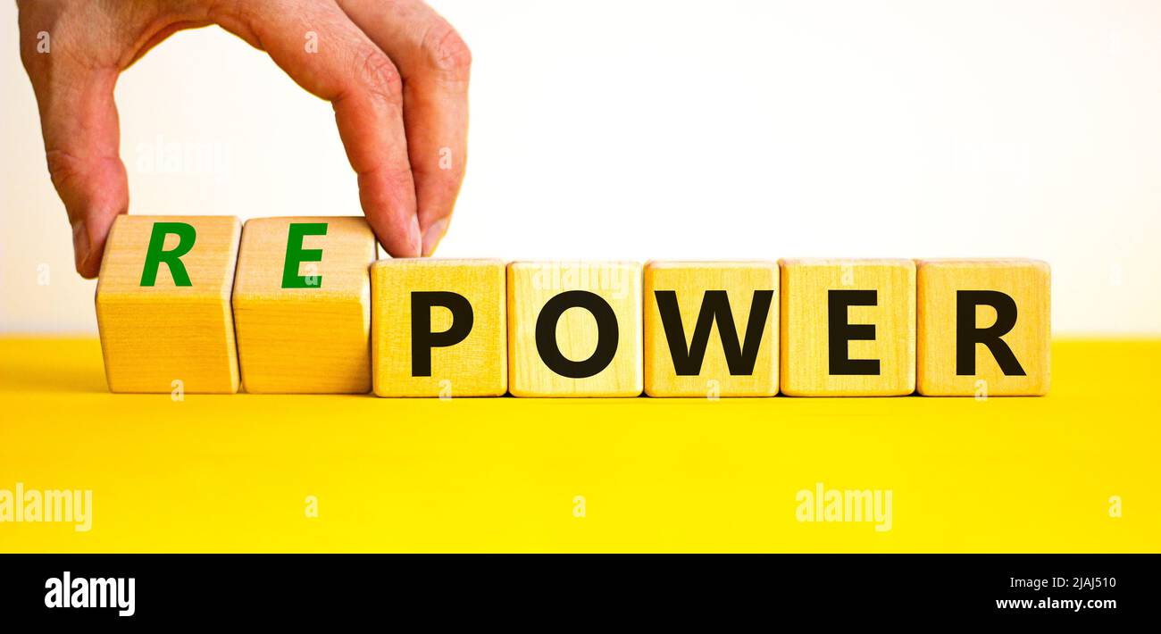 Power or repower symbol. Businessman turns wooden cubes and changes concept words Power to Repower. Beautiful yellow table white background. Business Stock Photo