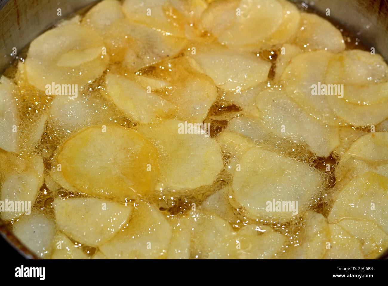 A close up of fried chips potatoes frying in boiling hot oil in a deep fryer at home. fast fries