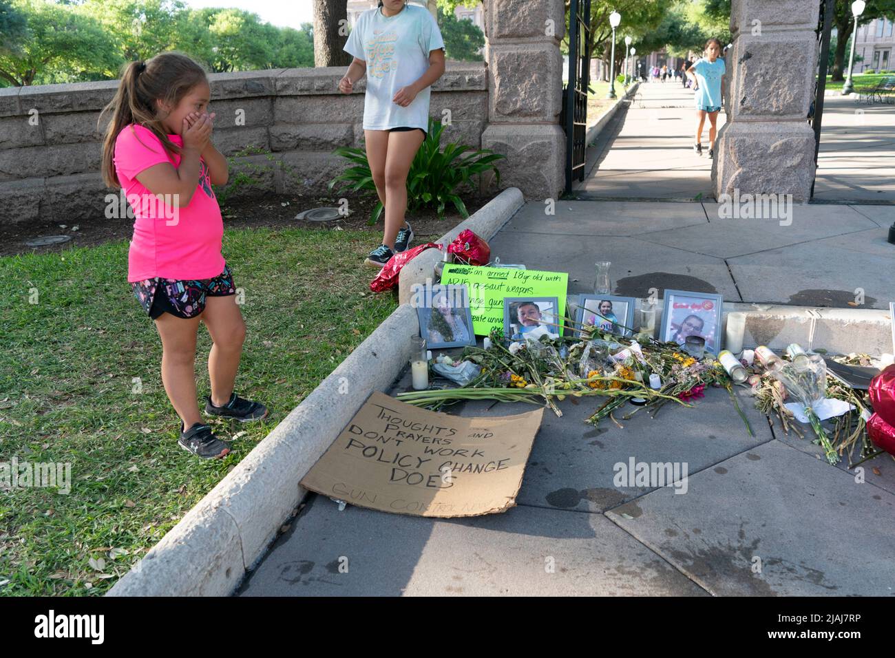 Austin Texas USA, May 30 2022: An elementary school-aged girl looks at photographs of many victims of the Uvalde, Texas mass murder at Robb Elementary, along with remembrance candles and bouquets of flowers at a makeshift memorial at the steps to the Texas Capitol grounds. Credit: Bob Daemmrich/Alamy Live News Stock Photo
