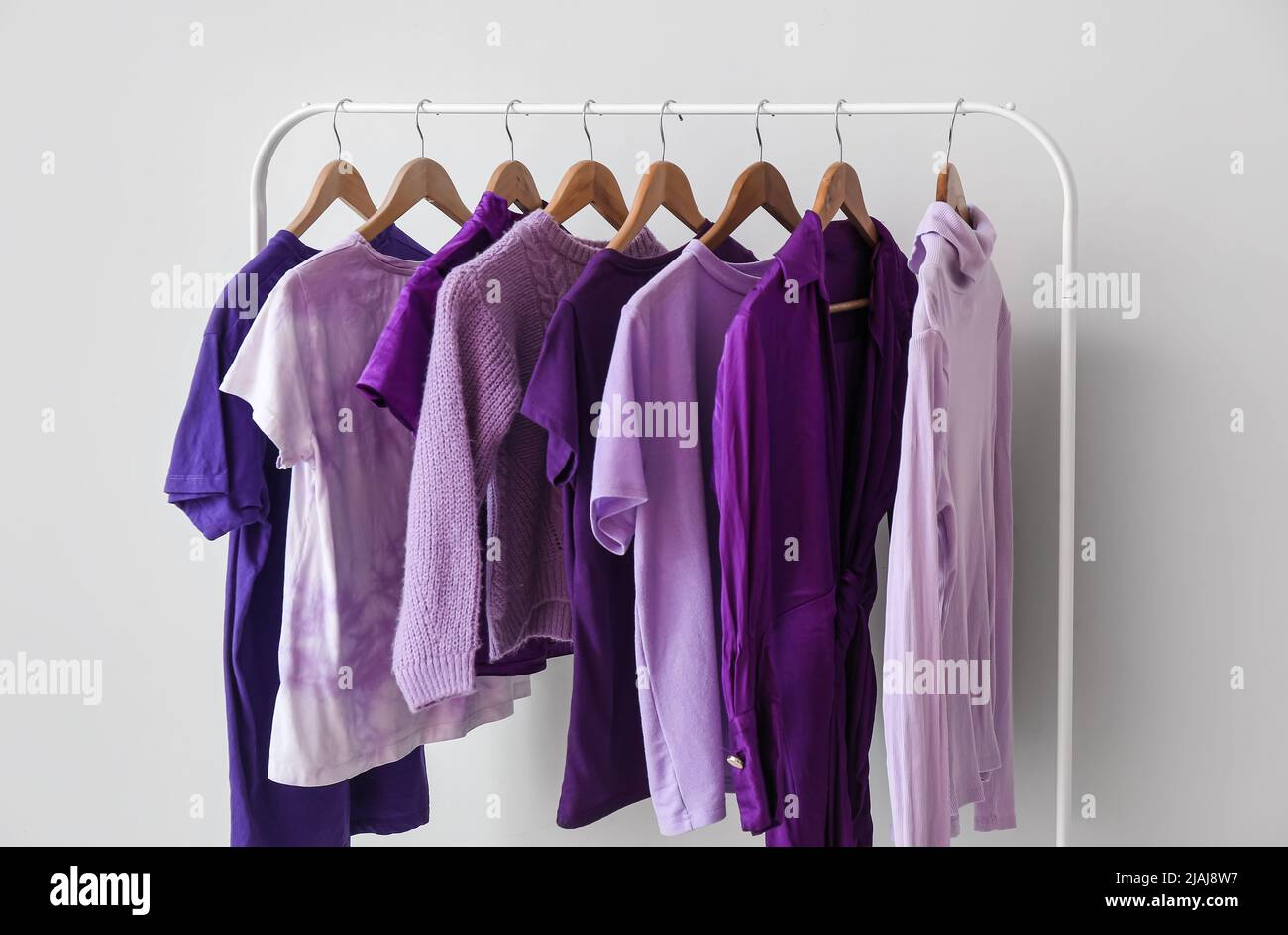 Purple Coat Rack Rack with clothes in purple shades near light wall Stock Photo - Alamy