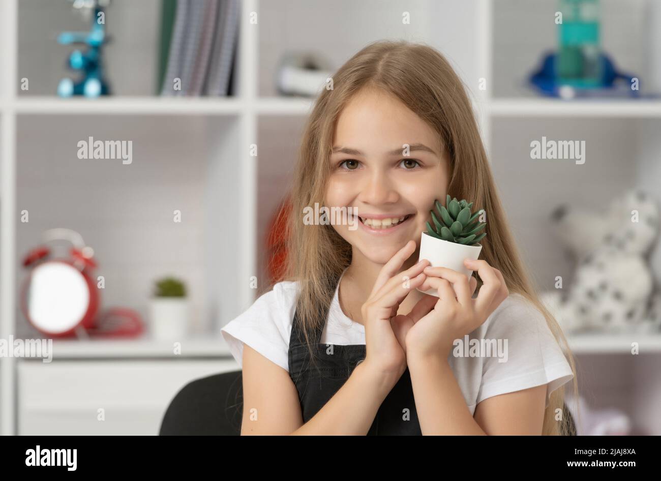 positive child hold potted plant in school classroom Stock Photo