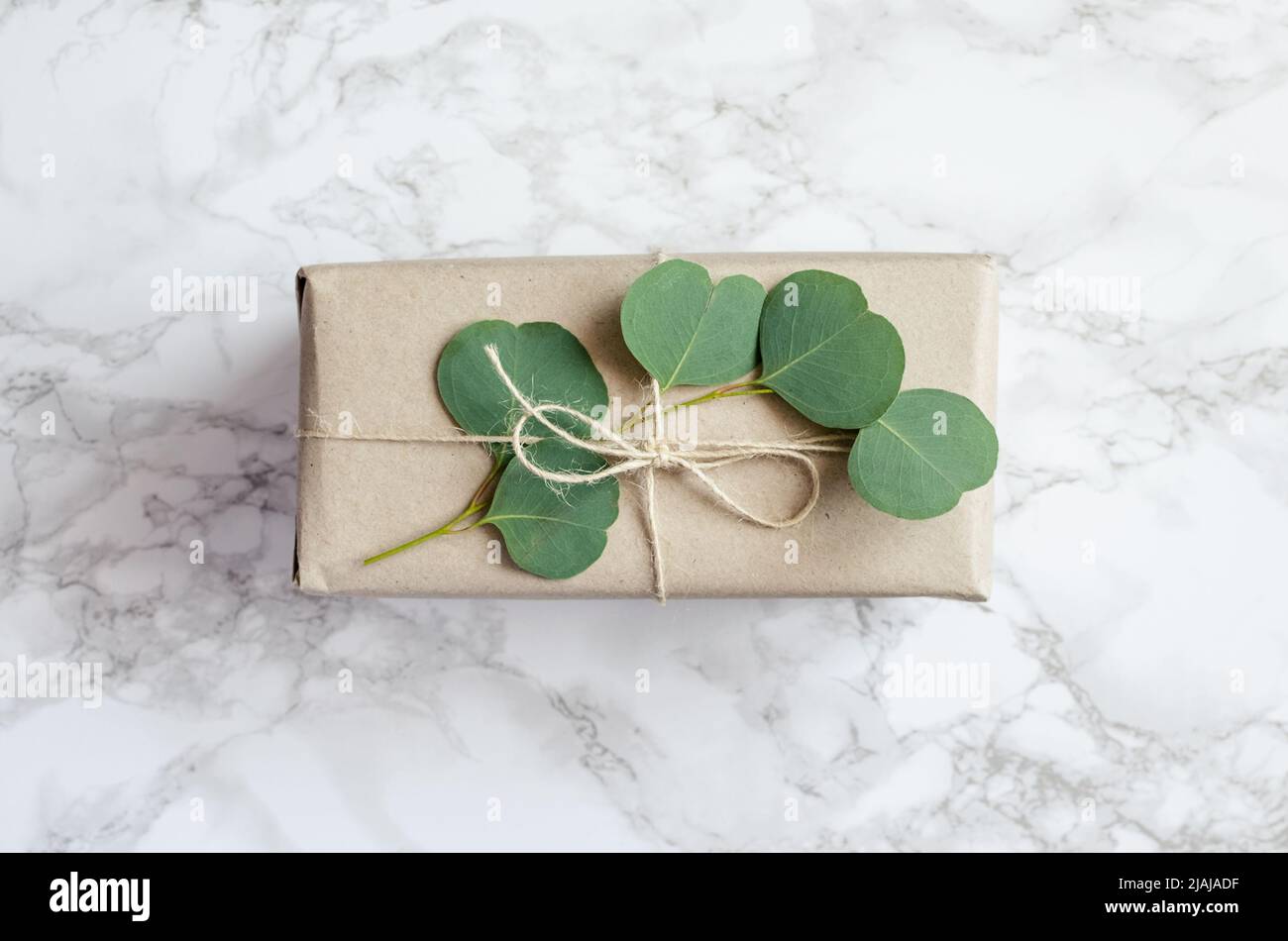 Gift box wrapped in brown paper decorated with eucalyptus branch, natural eco friendly zero waste gift wrapping idea. Top view. Stock Photo