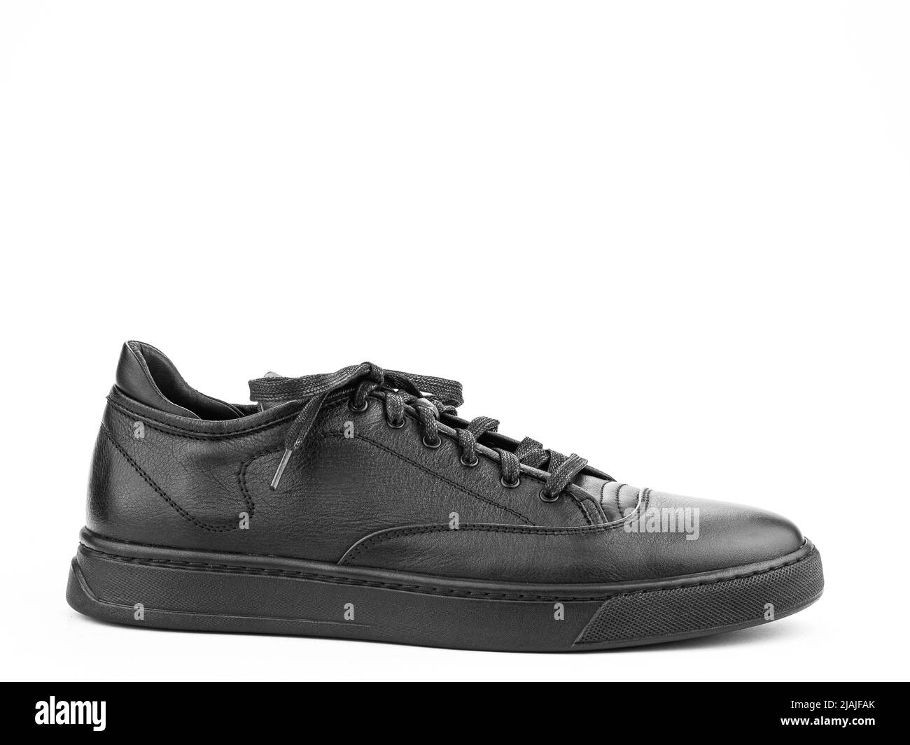 Black leather classic sneakers with laces. Casual men's style. Black rubber soles. Isolated close-up on white background. right side view Stock Photo