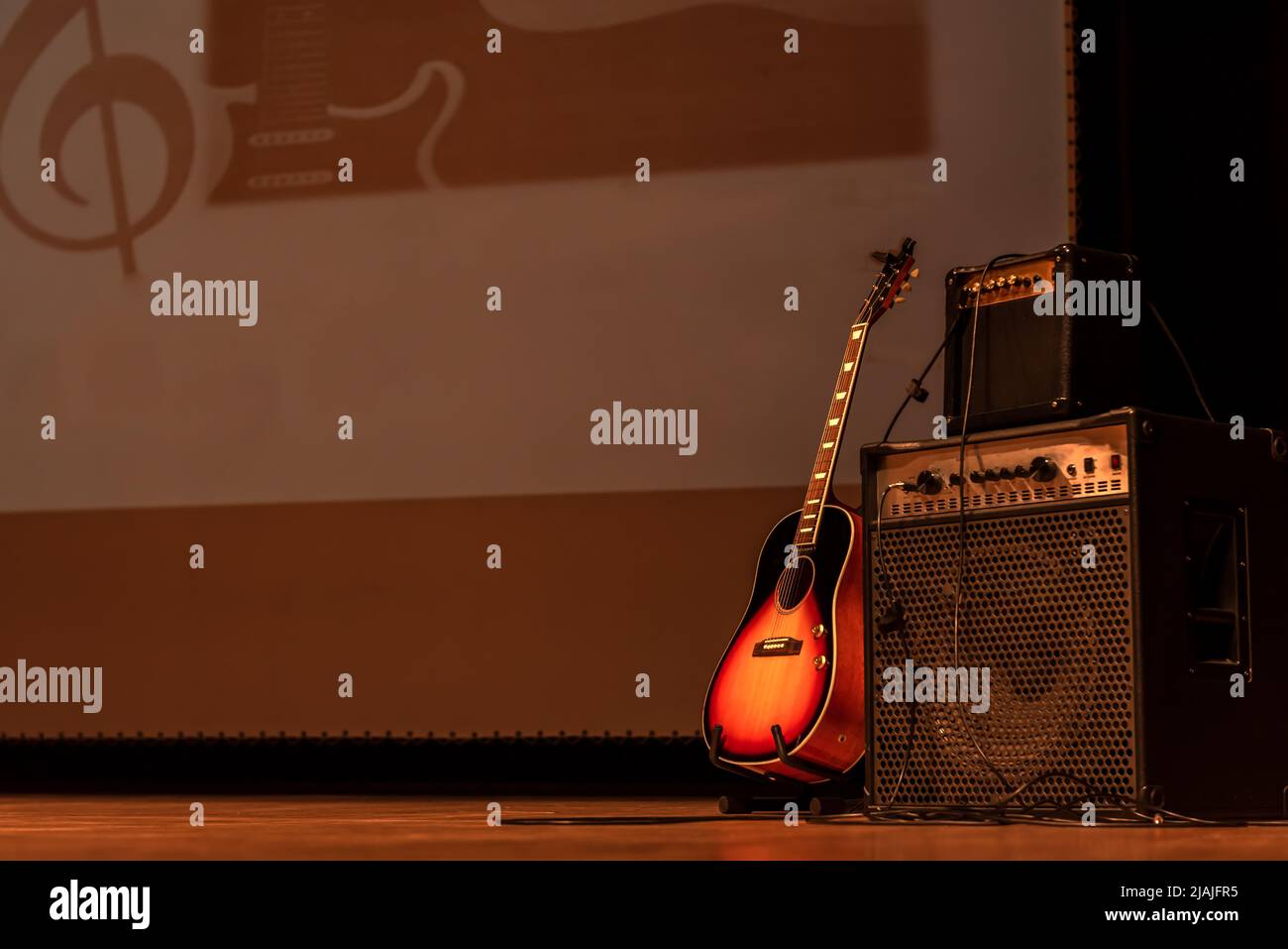 acoustic guitar on guitar stand with two amplifiers next to it im spain Stock Photo