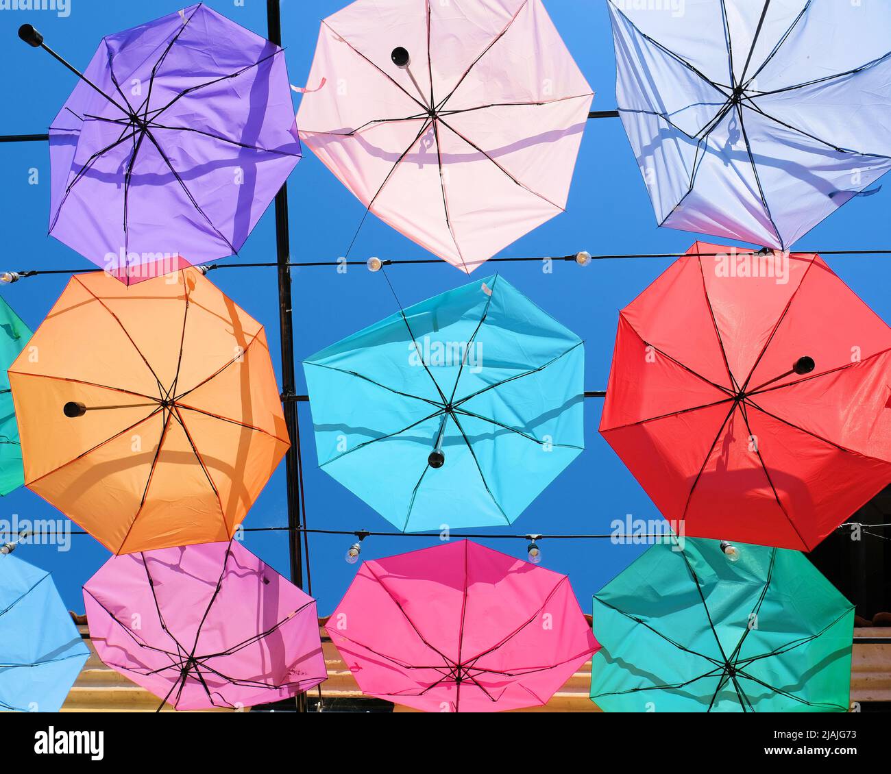 Umbrellas hanging from cables creating a ceiling effect; rows of