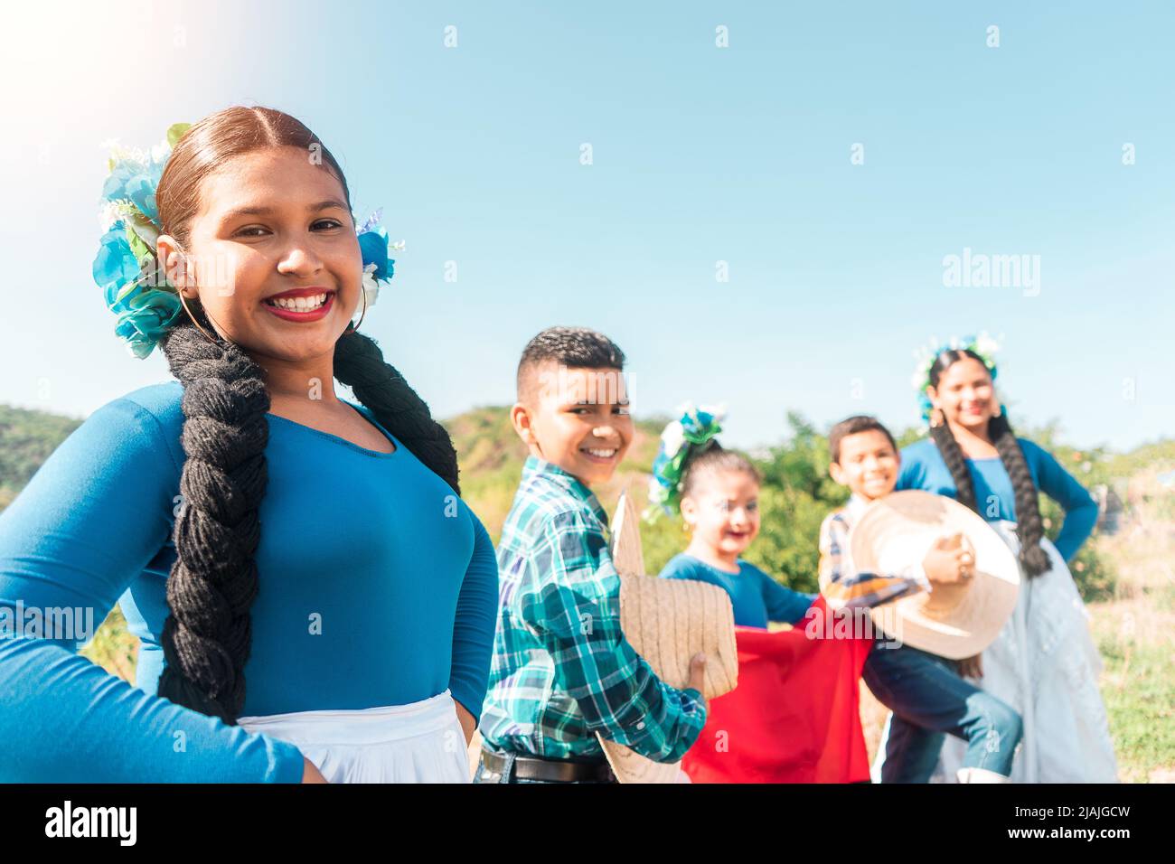 Group of Latino teens, men and women, dressed in traditional country clothing posing on a mountain in Nicaragua smiling Stock Photo