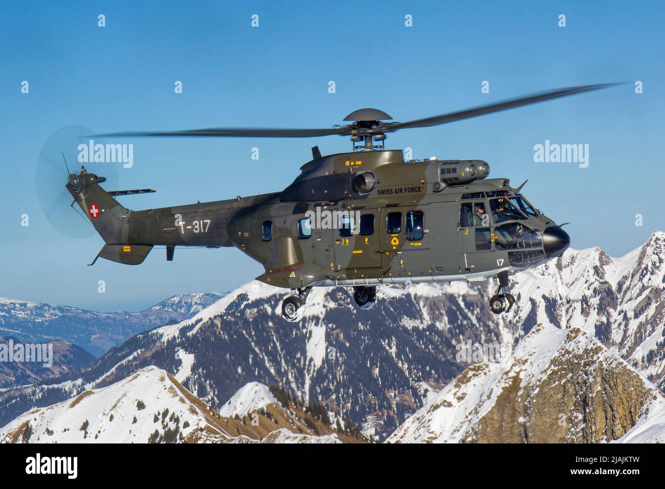 A Swiss Air Force AS332 Super Puma tactical transport helicopter flying in the Swiss Alps. Stock Photo
