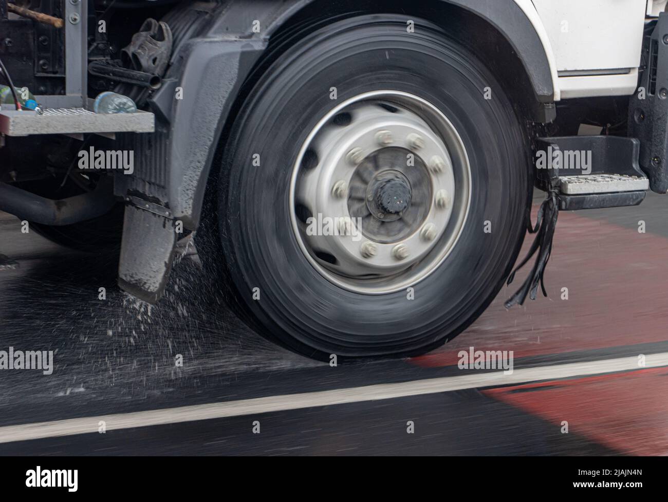 Detail of the wheel of a truck driving in the rain on a wet road. Stock Photo