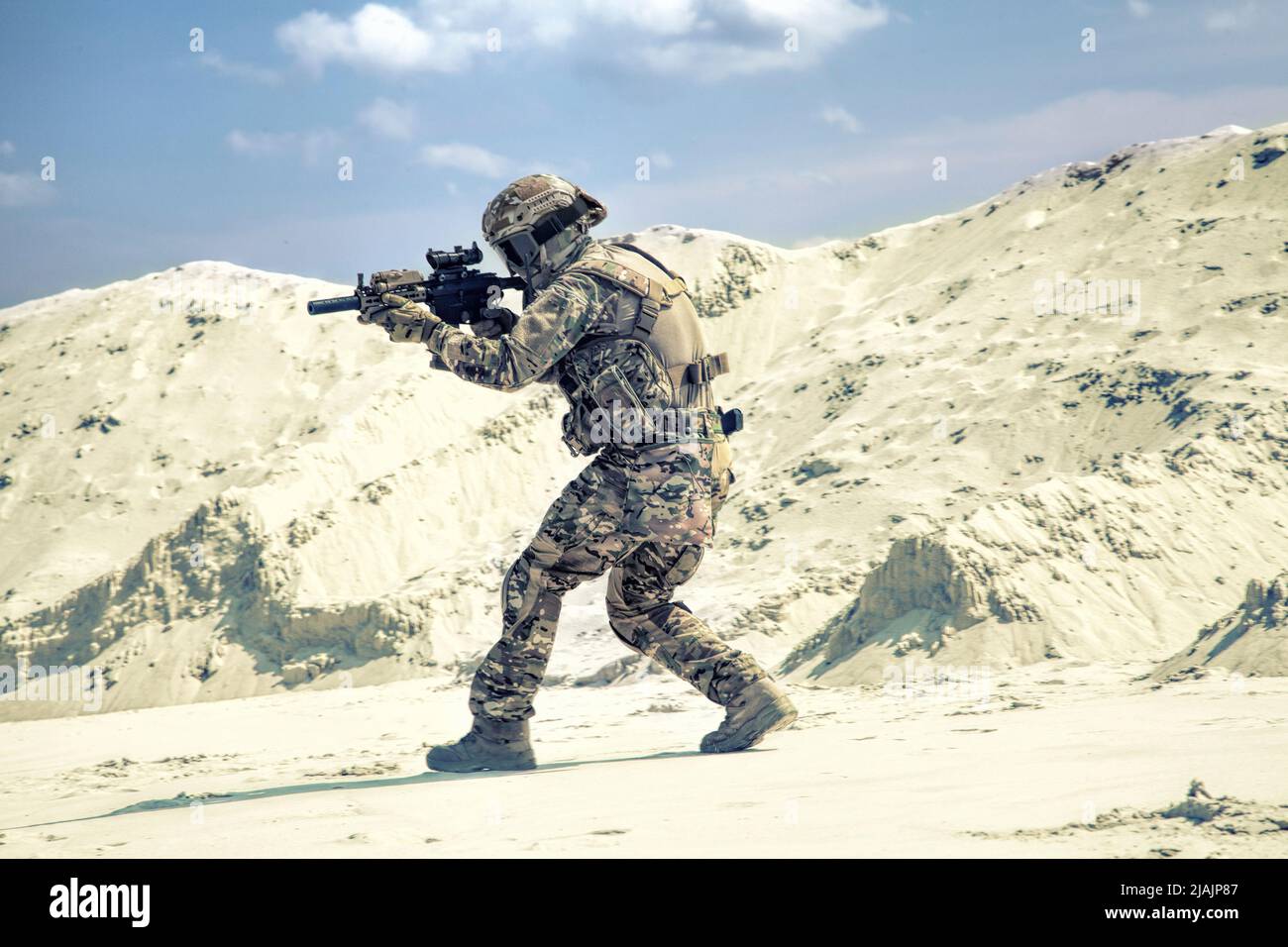 Man in military camouflage uniform during armed conflict in a desert area. Stock Photo