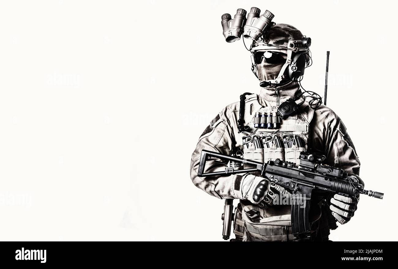 Studio shot of a serviceman equipped with night vision device, radio headset, and short barrel rifle. Stock Photo