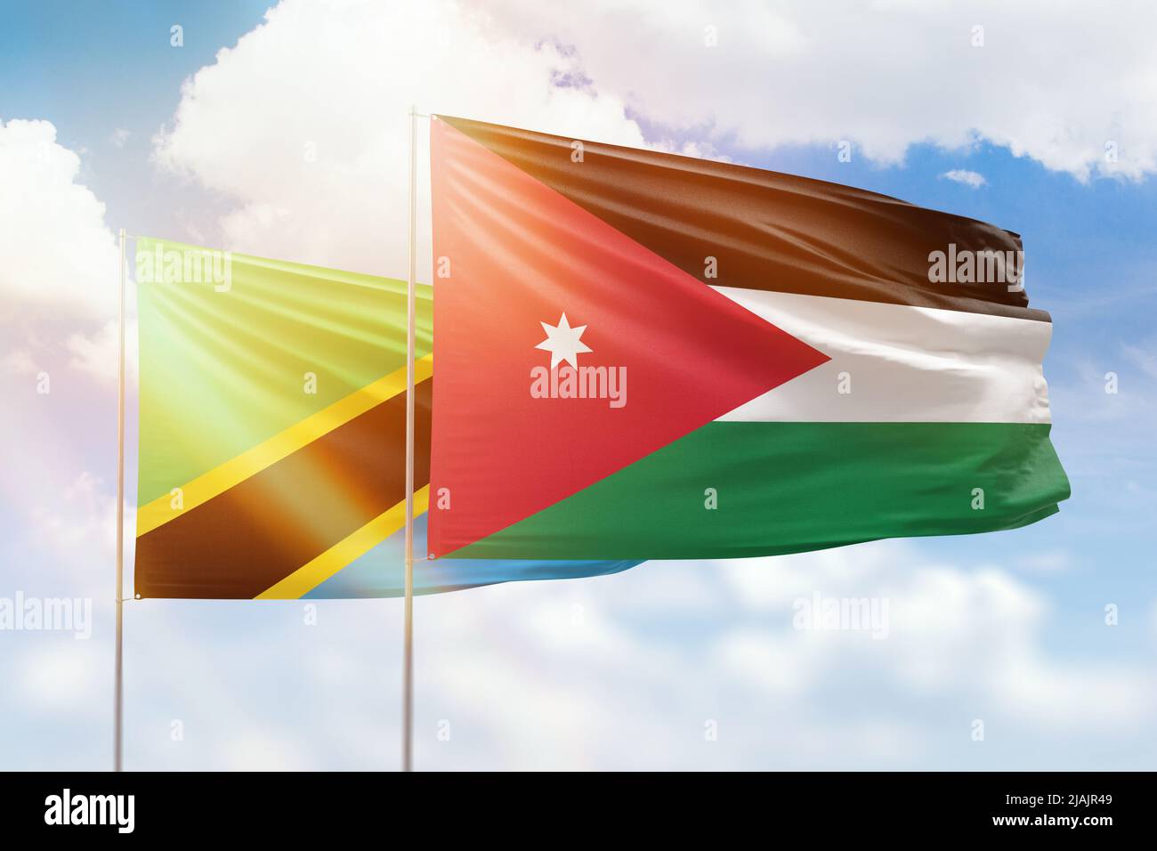Sunny blue sky and flags of jordan and tanzania Stock Photo