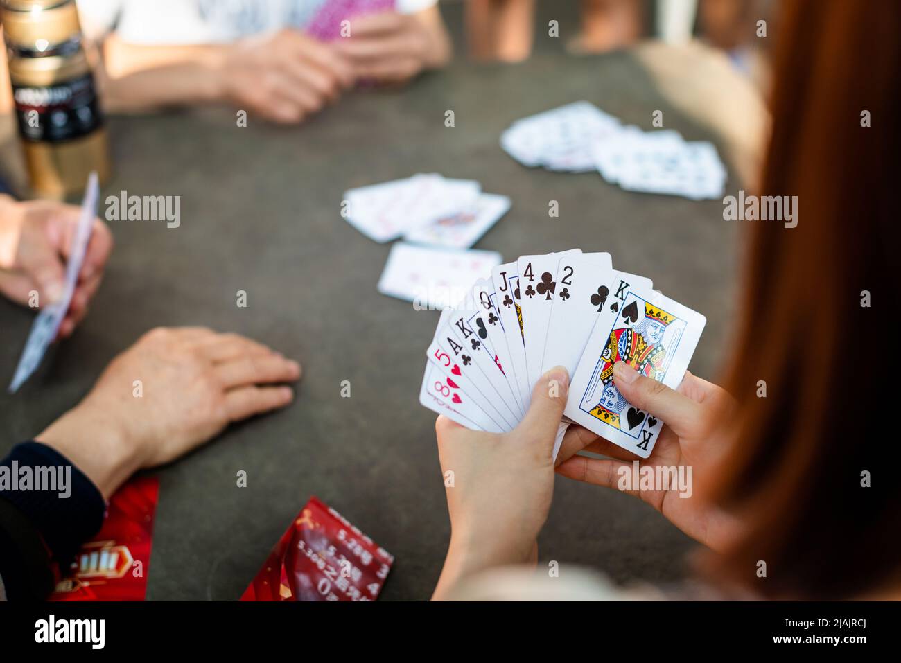 Young woman playing cards with senior Chinese people Stock Photo