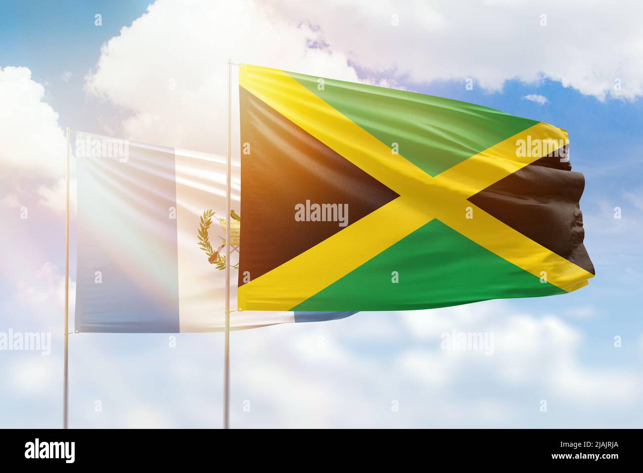 Sunny blue sky and flags of jamaica and guatemala Stock Photo
