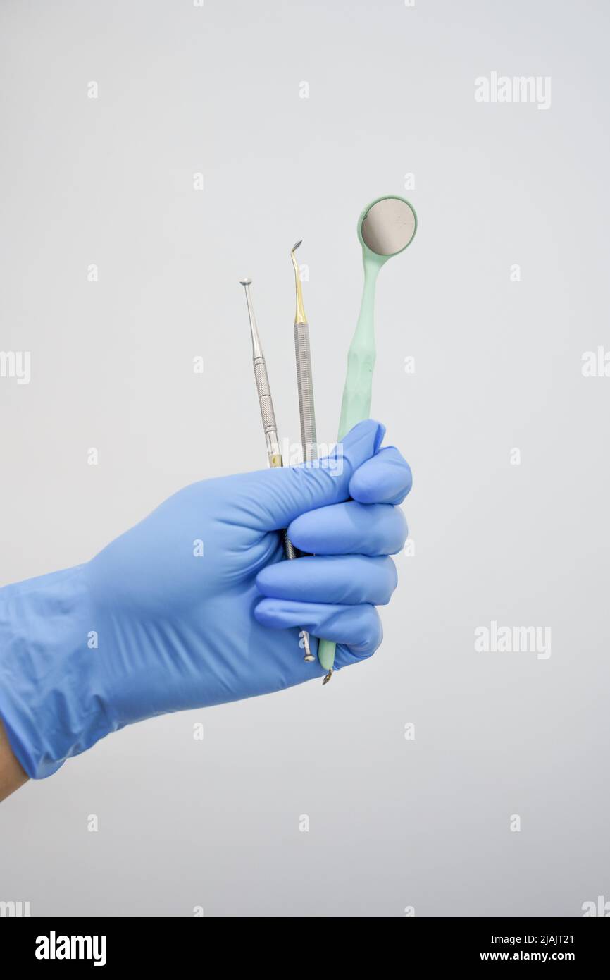 gloved hand holds professional dental instruments including mirror