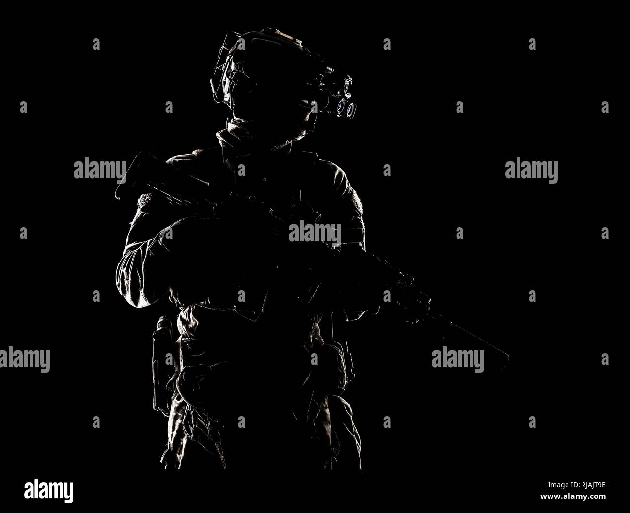 Special forces fighter standing in darkness with service rifle and