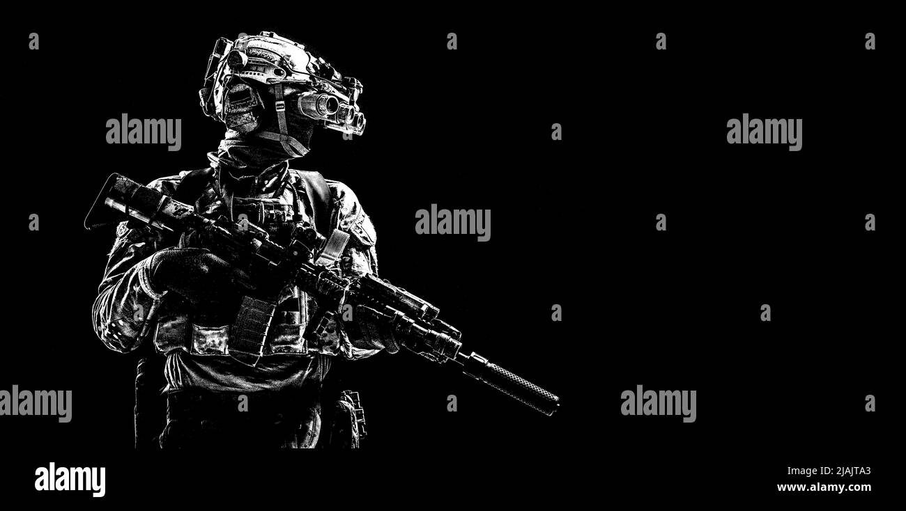 Special forces soldier standing in darkness equipped with night vision goggles and assault rifle. Stock Photo