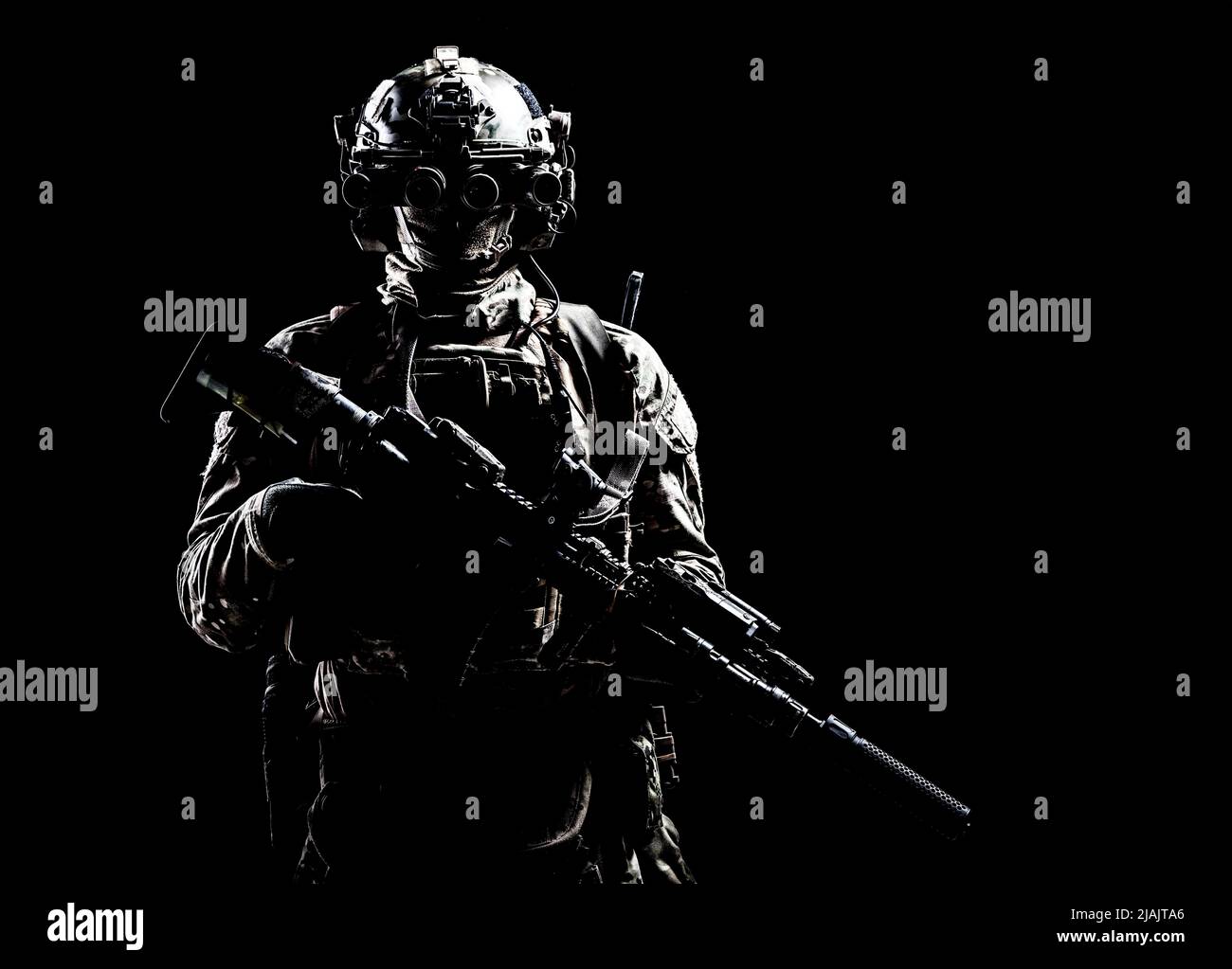 Special forces soldier standing in darkness equipped with night vision goggles and assault rifle. Stock Photo