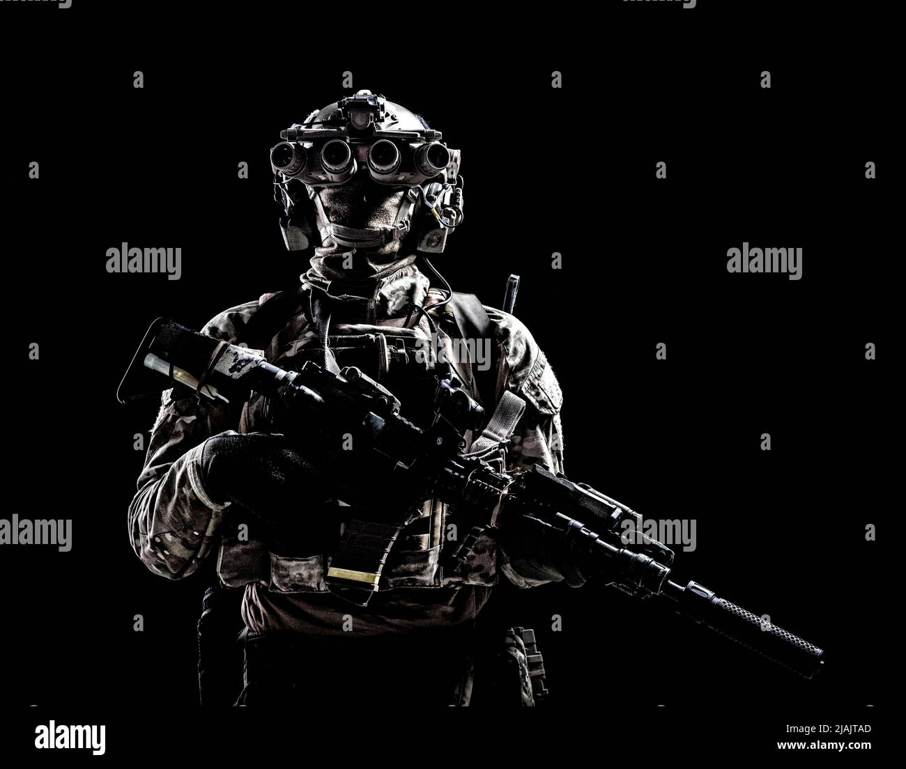 Special forces soldier standing in darkness equipped with night vision goggles and assault rifle. Stock Photo