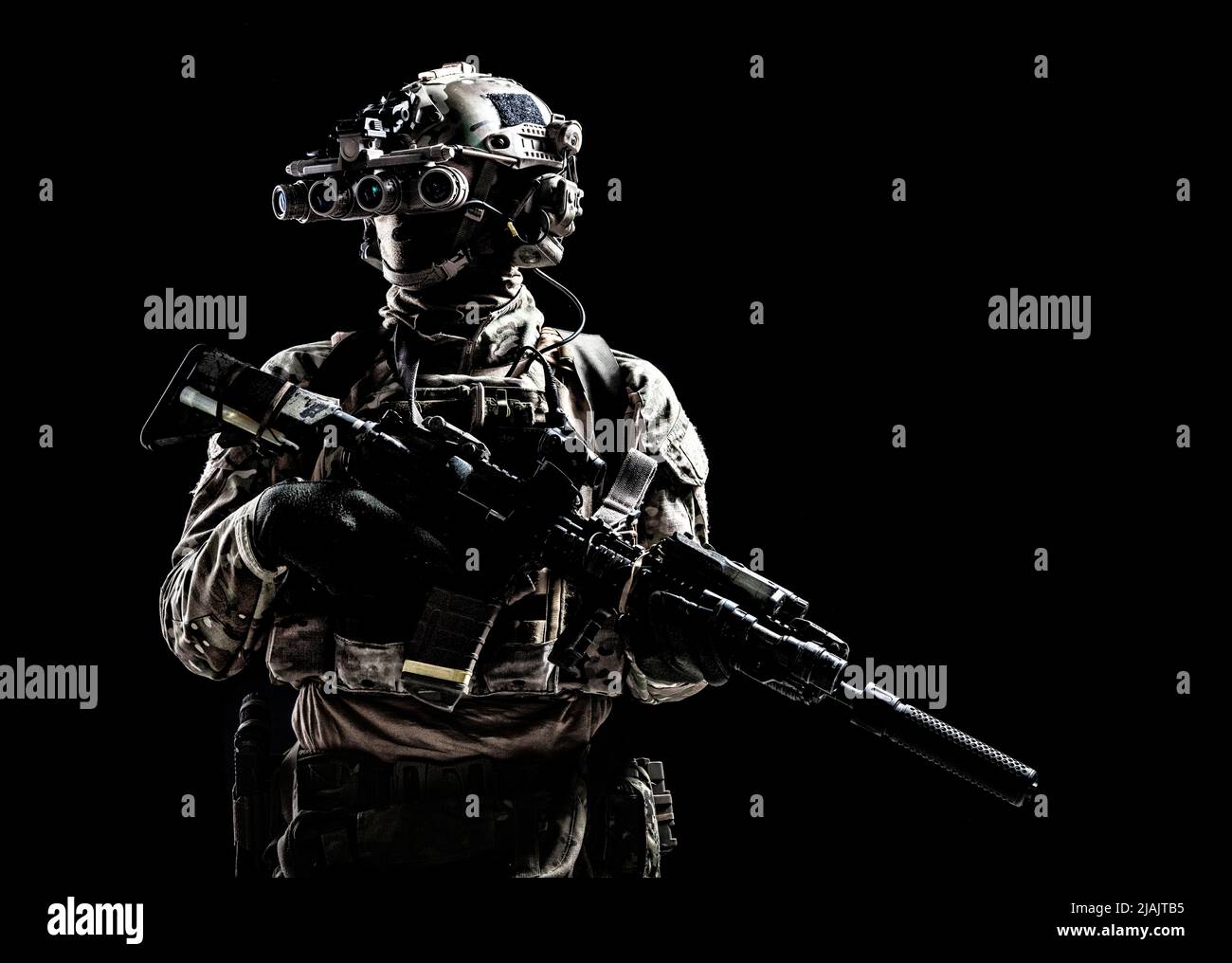 Special forces soldier standing in darkness equipped with night vision goggles and assault rifle. Stock Photo