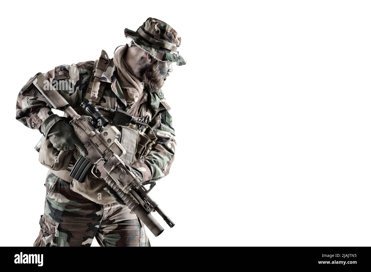 Commando soldier in camouflage uniform and boonie hat, armed with service rifle, studio shot on white background. Stock Photo