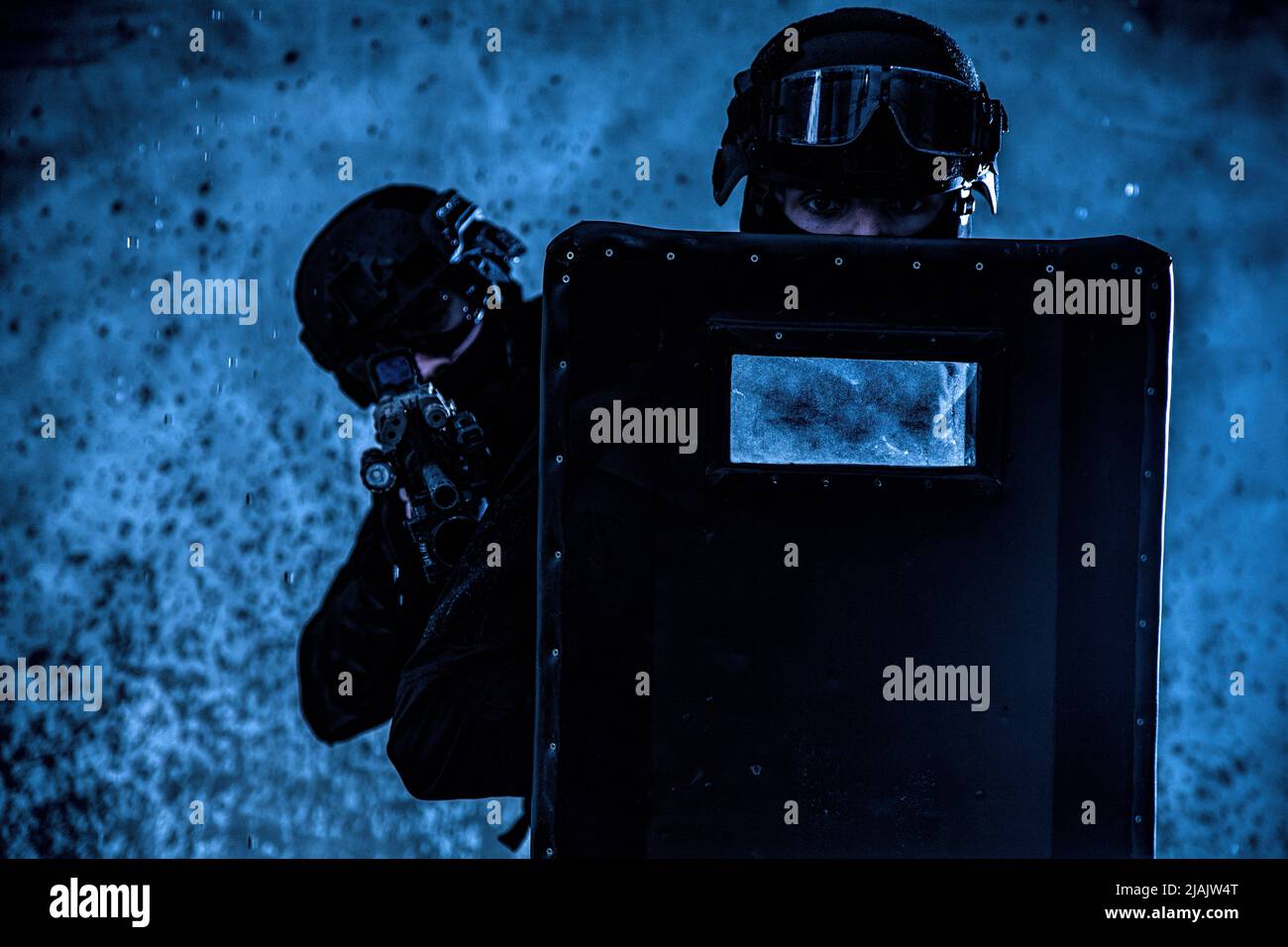 SWAT team officers protecting themselves behind ballistic shield as they move through a firefight. Stock Photo