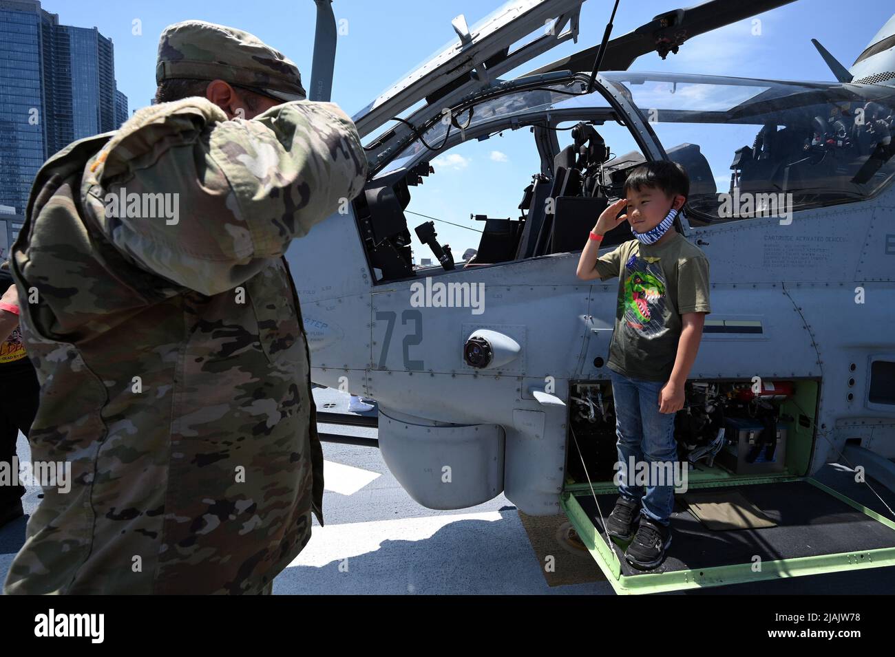 New York, USA. 30th May, 2022. Teddy Oh, 7, salutes as he stands next to a Navy Cobra attack helicpter on flight deck of the Nay's USS Bataan (LHD-5) Wasp-class amphibious assault ship on Memorial Day, New York, NY, May 30, 2022. The USS Bataan and other vessels participated in Fleet Week which returned this year for the first time since the start of the COVID-19 Pandemic. (Photo by Anthony Behar/Sipa USA) Credit: Sipa USA/Alamy Live News Stock Photo