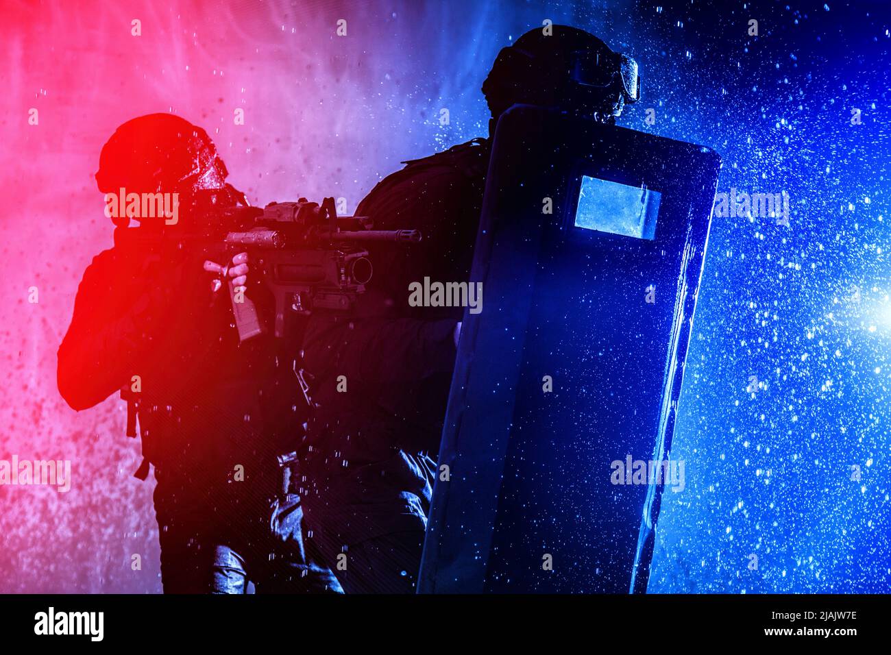 SWAT team officers protecting themselves behind ballistic shield as they move through a firefight. Stock Photo