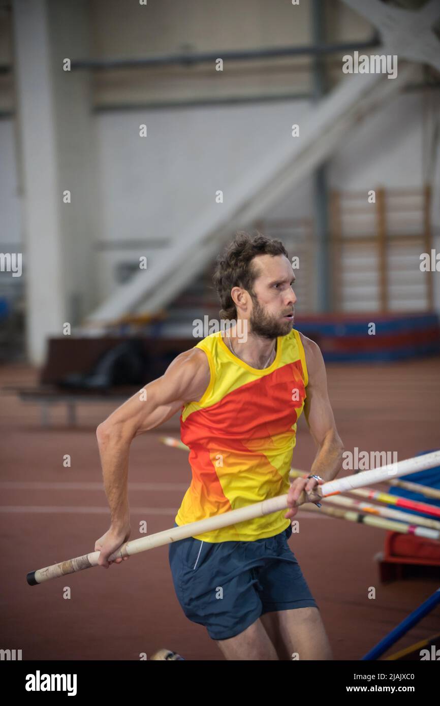 Pole vaulting indoors an athletic man running on the track with a