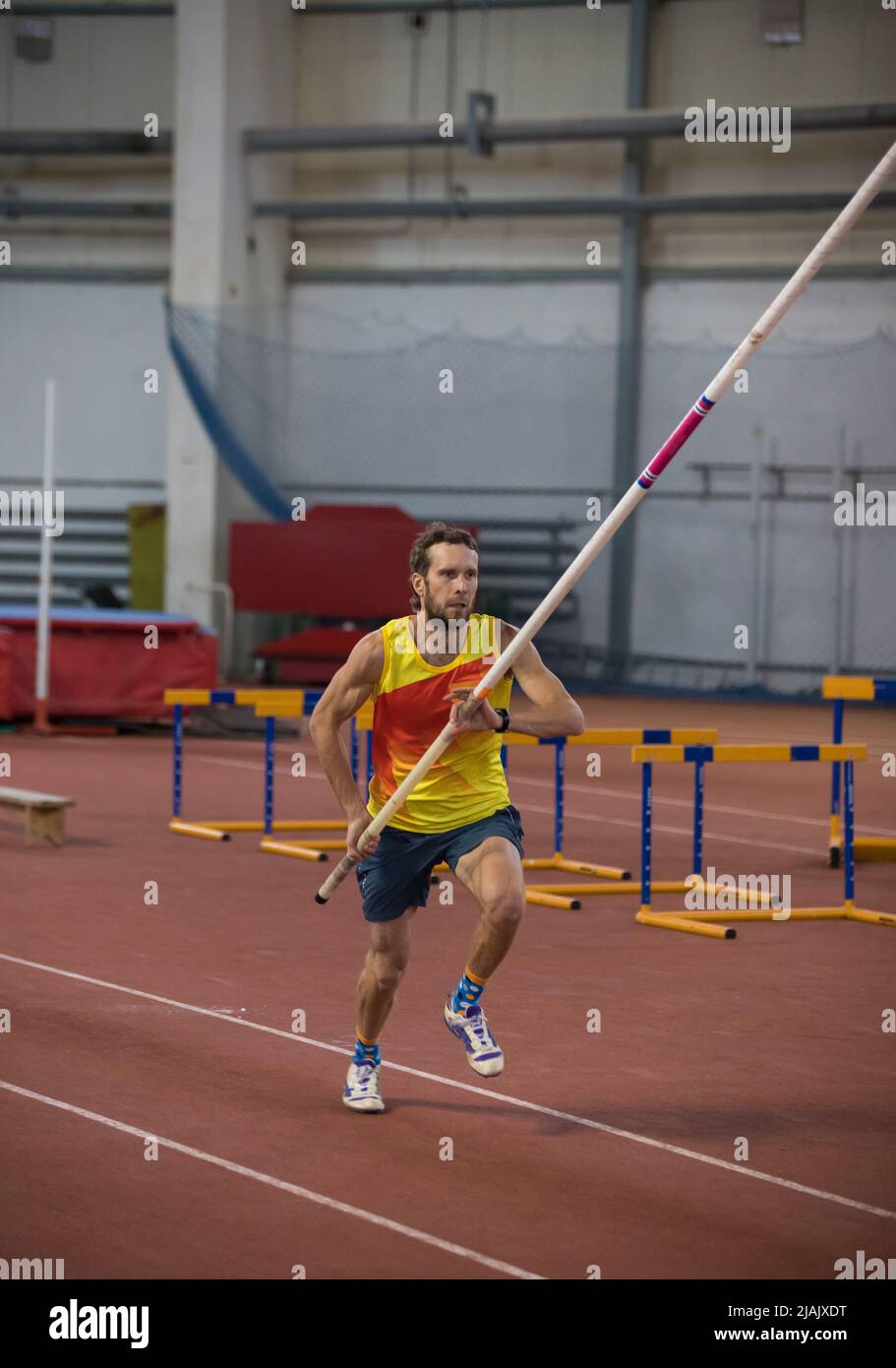 Pole Vaulting Indoors - A Man In Yellow Shirt Running On The Track With ...