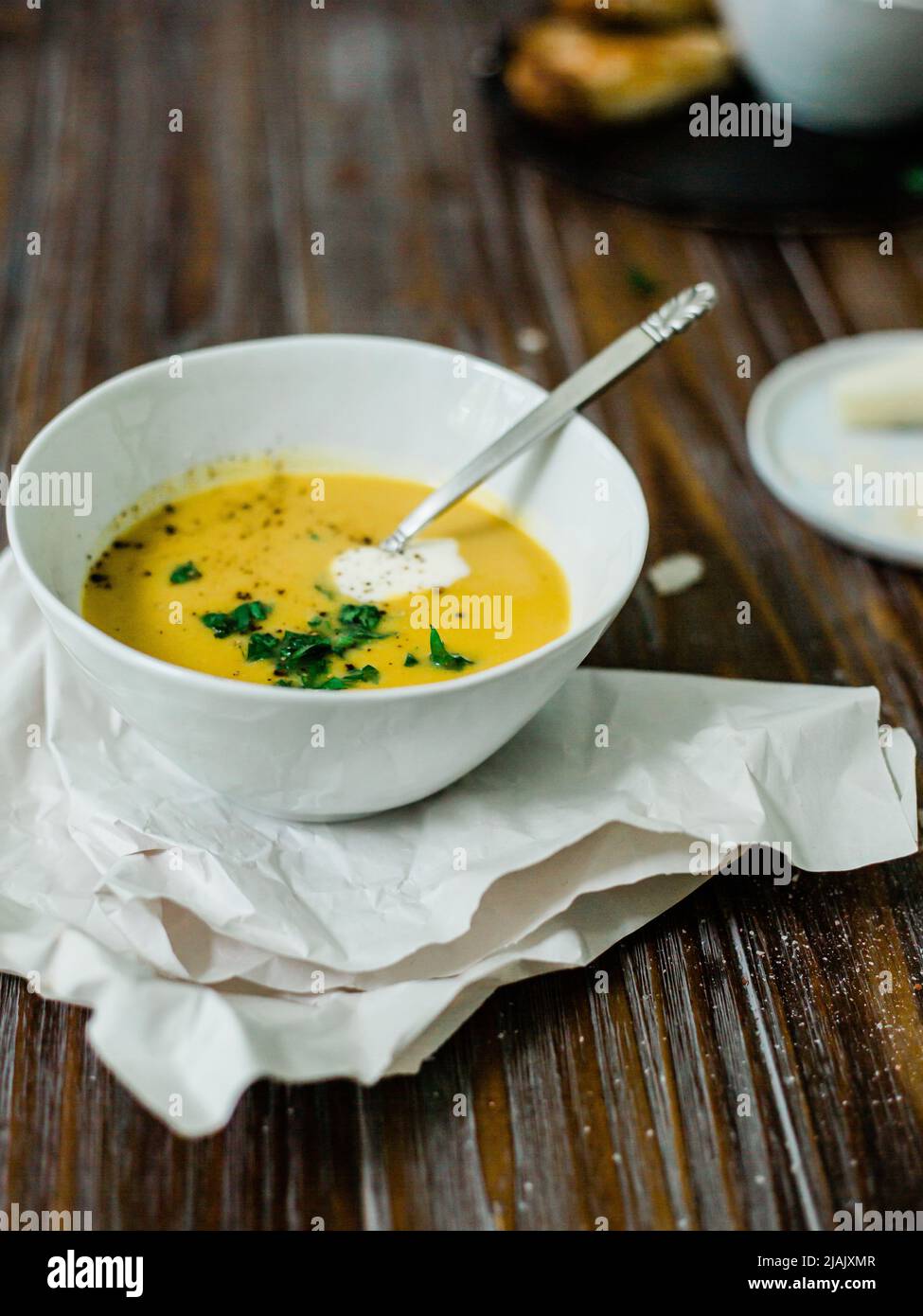 Butternut squash soup on a wood table with linen napkins and a cozy