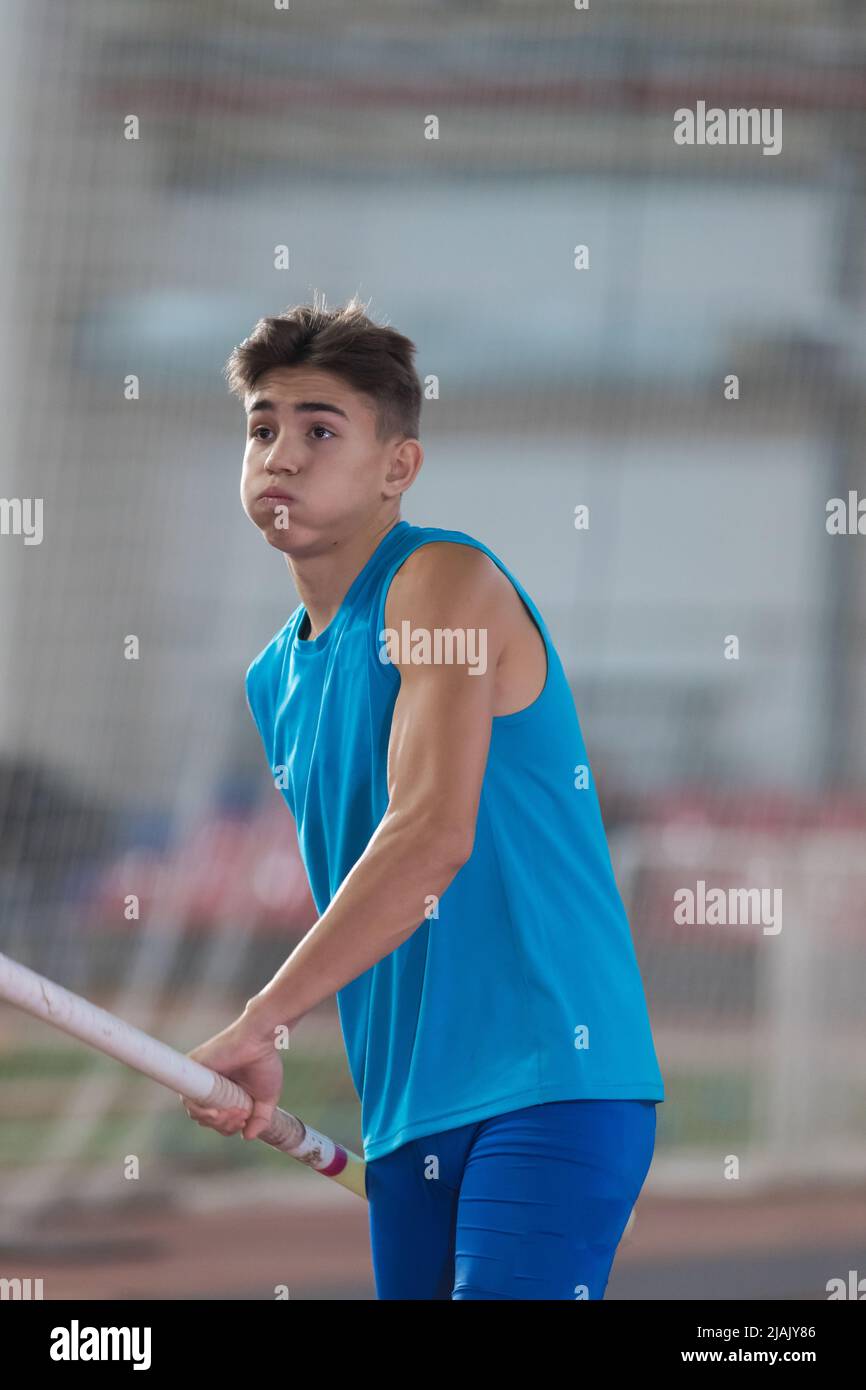 Pole vaulting indoors young man running up holding a pole took a
