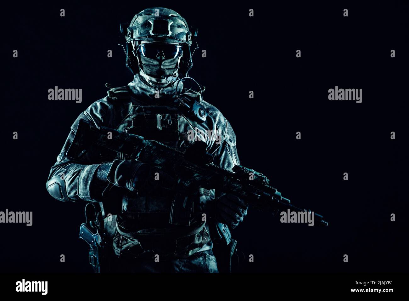 Special operations forces soldier wearing mask, armed with submachine gun, on black background