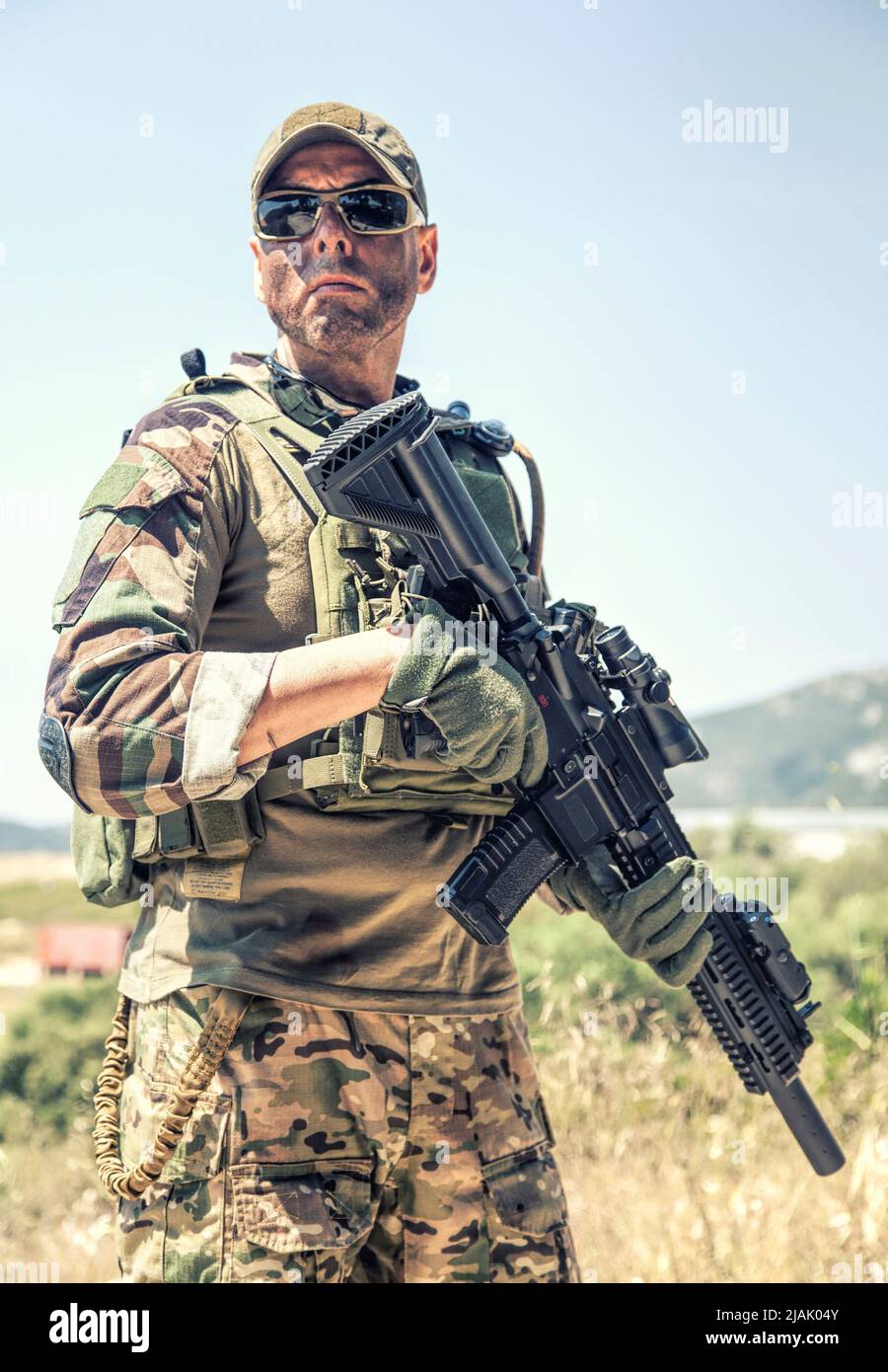 Half-length portrait of an armed Navy SEALs fighter wearing ballistic goggles while standing outdoors. Stock Photo