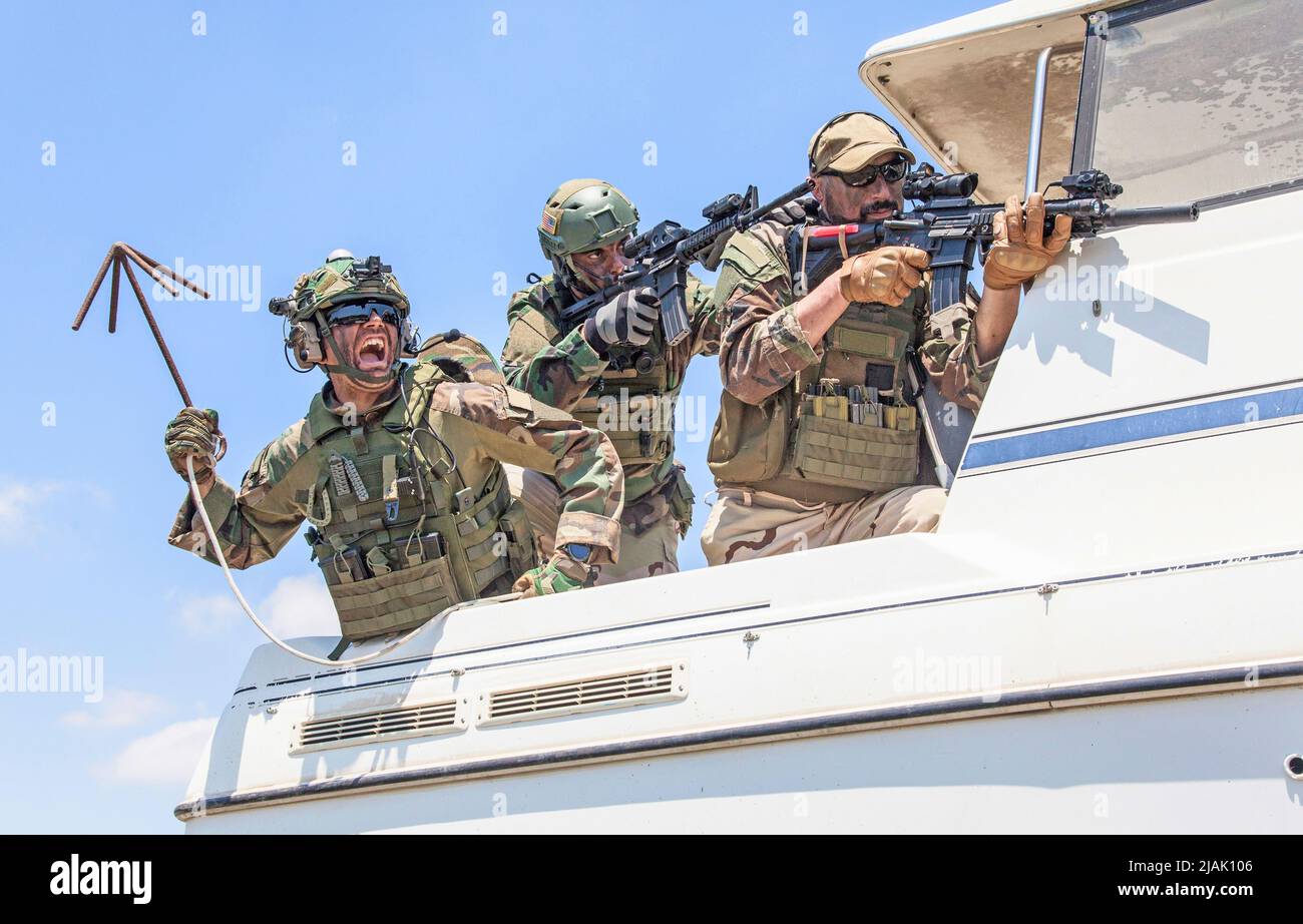 Navy SEALs standing together on stern of speed boat. Stock Photo