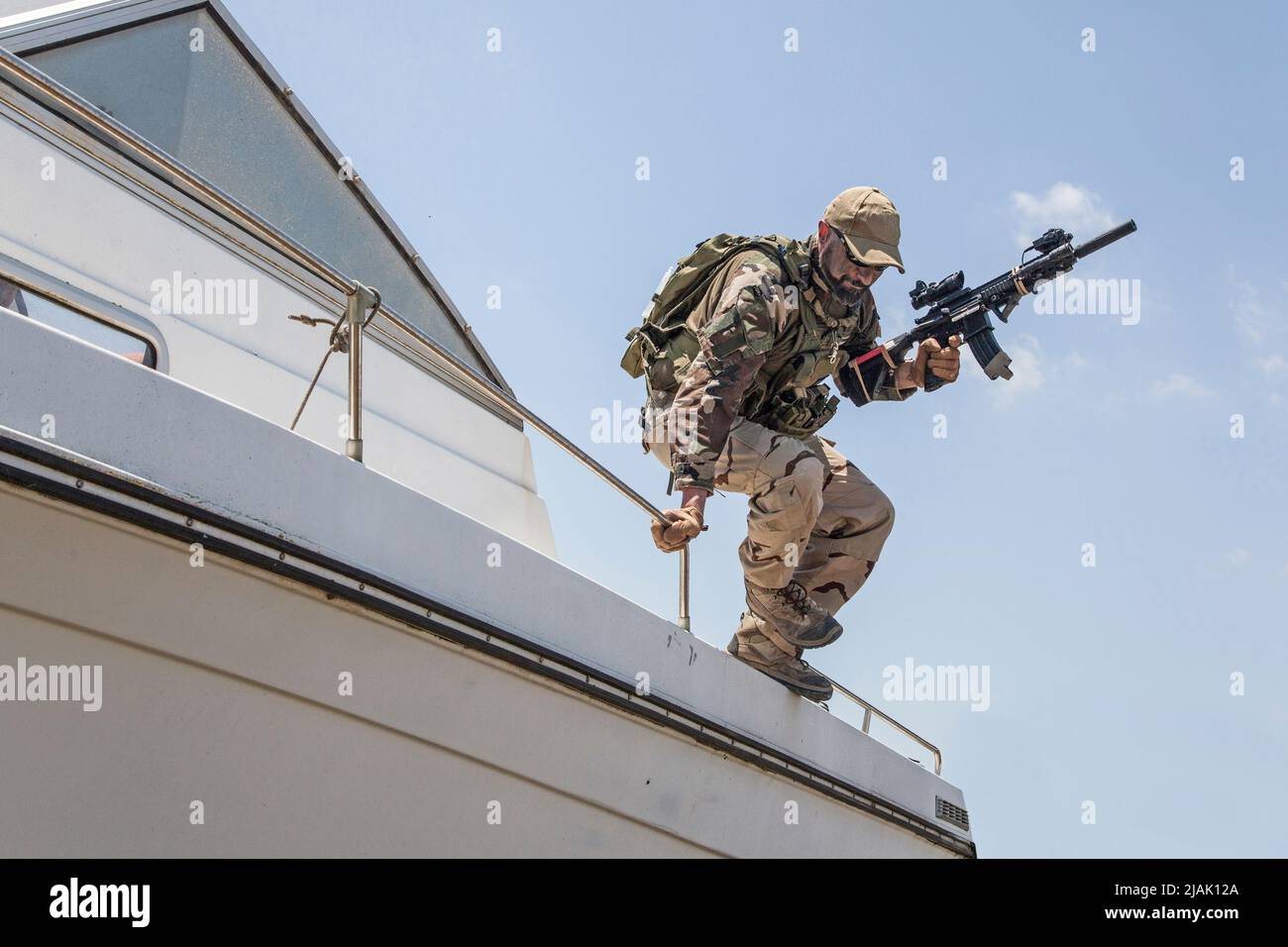 Special forces soldier jumping from a speed boat deck, landing on shore with assault rifle. Stock Photo