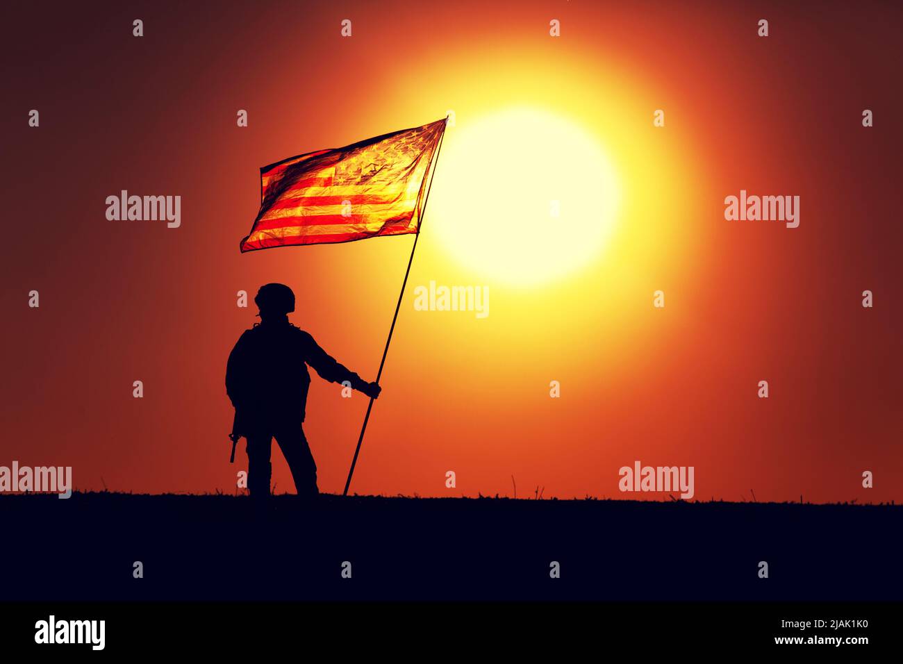 Silhouette of a U.S. Army soldier standing on sunset horizon, waving ...