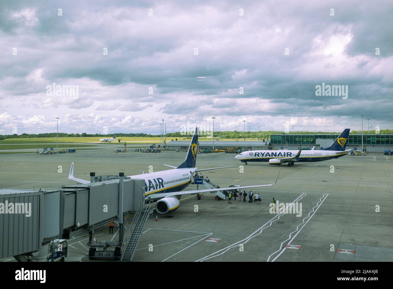 People boarding Ryanair airplane at London Stansted airport tarmac while another aircraft taxiing Stock Photo