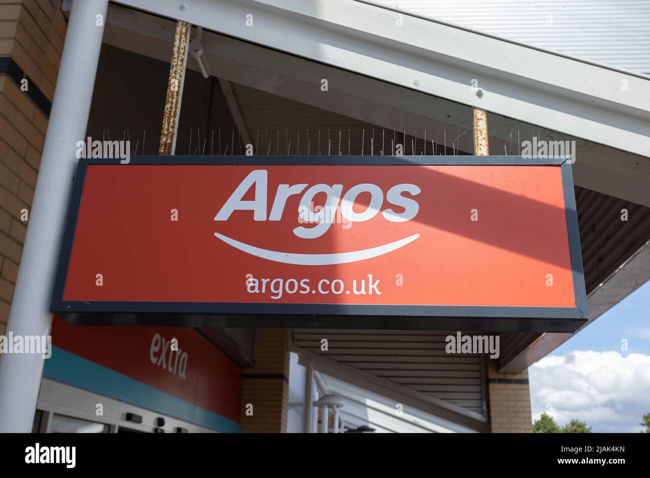 Red Argos shop sign with pigeon spikes on top. Argos is a British