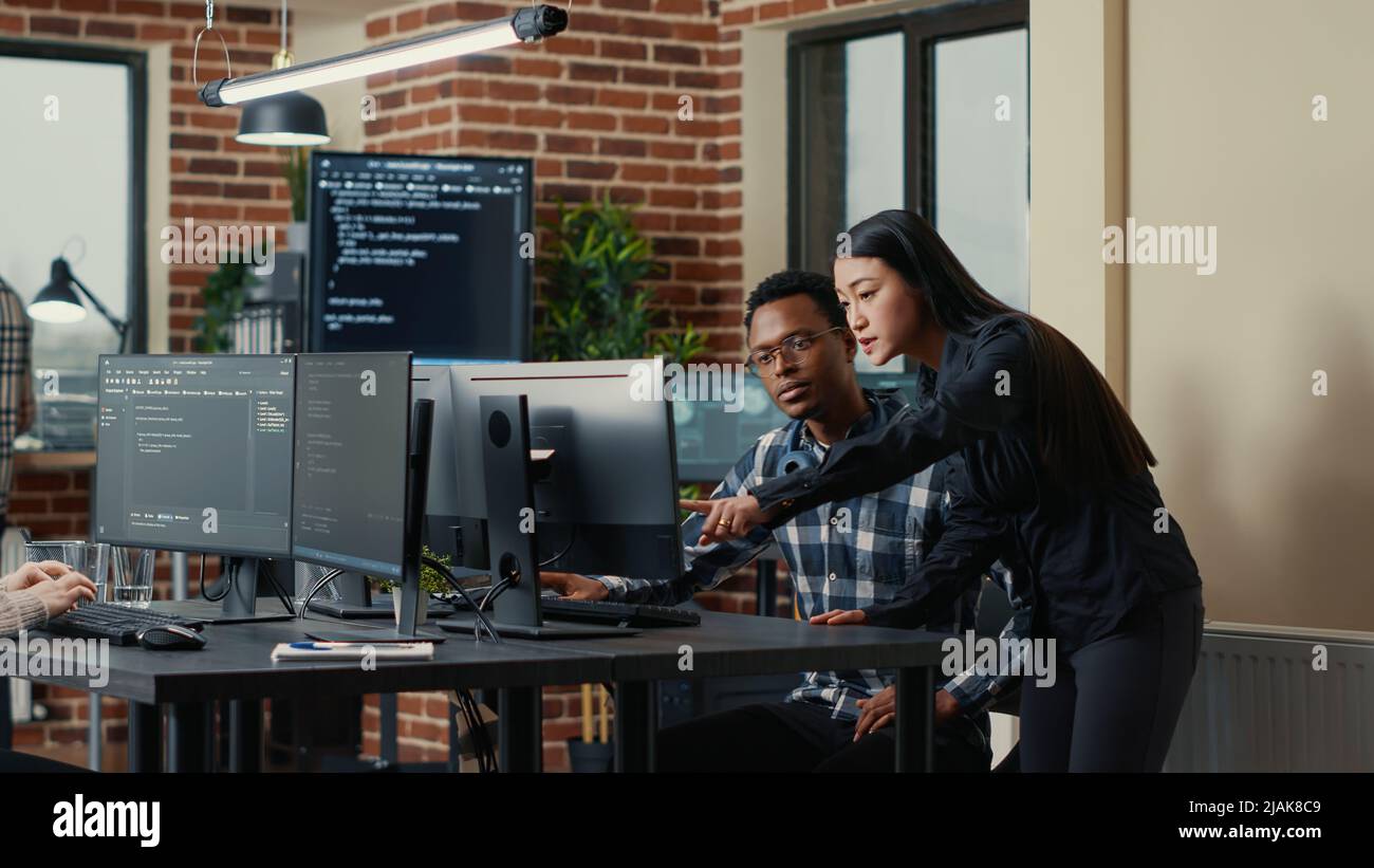 Two software developers holding laptop with coding interface walking