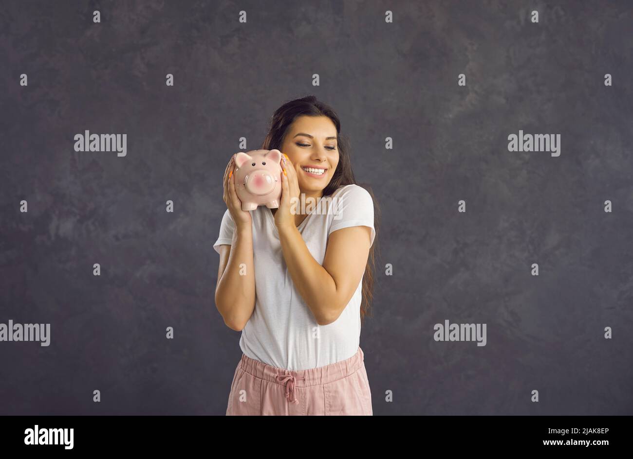 Smiling Latin woman hold piggybank with money saving Stock Photo