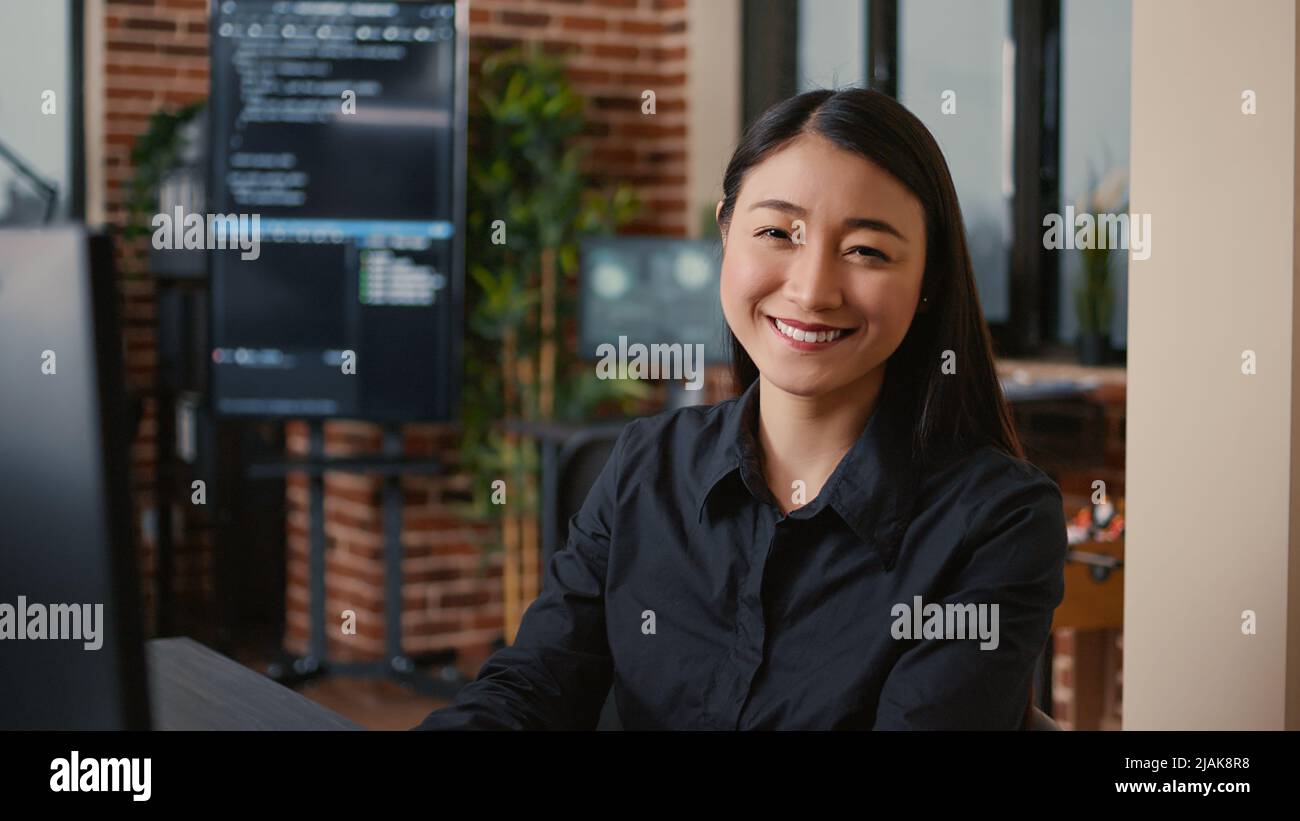 Smiling software developer typing machine learning app code on computer keyboard sitting at desk in big data office. Friendly cloud programer working casually in cyber security agency. Stock Photo