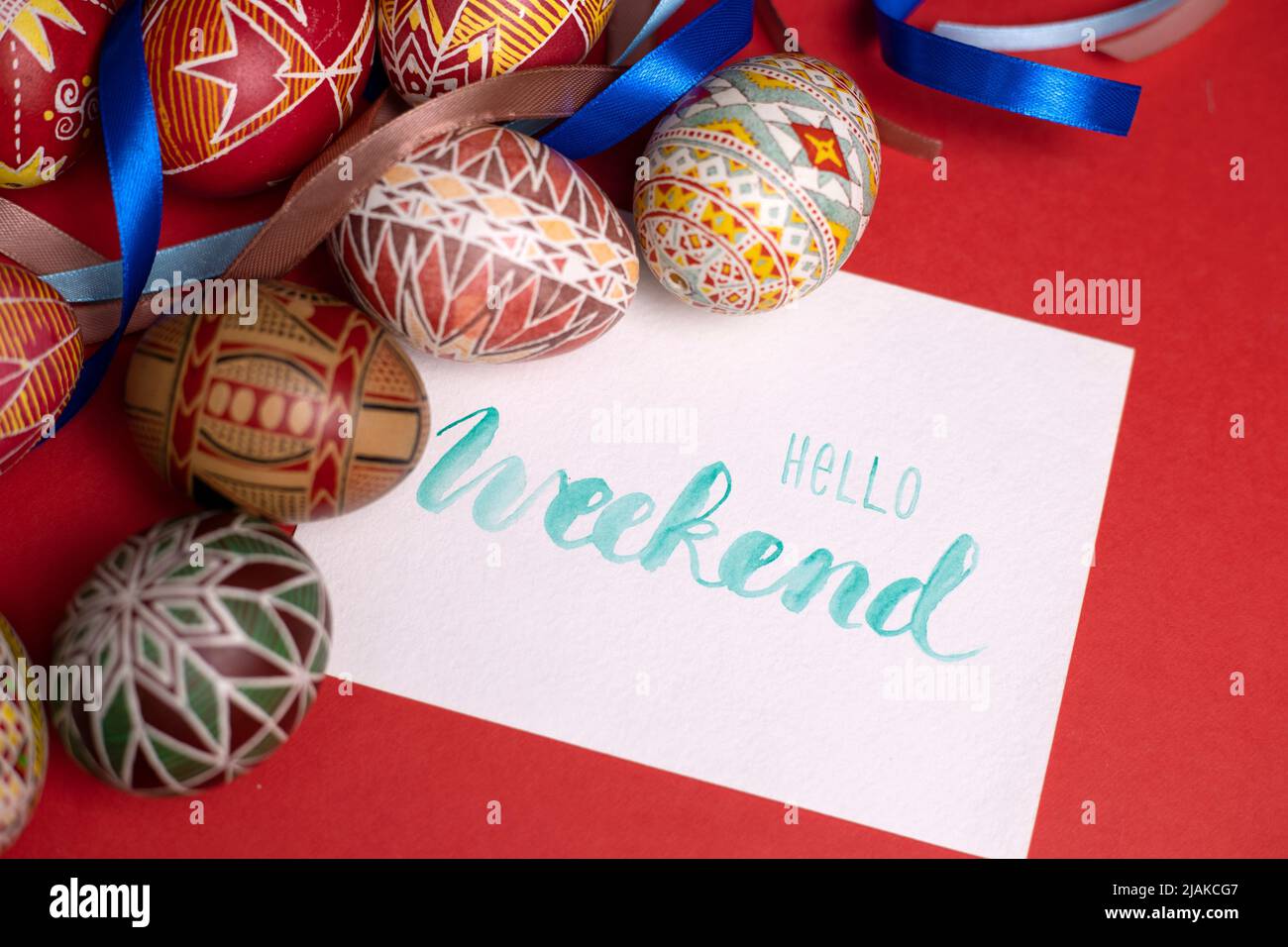happy easter card. beautiful Easter egg Pysanka handmade on a red background with the inscription hello weekend Stock Photo