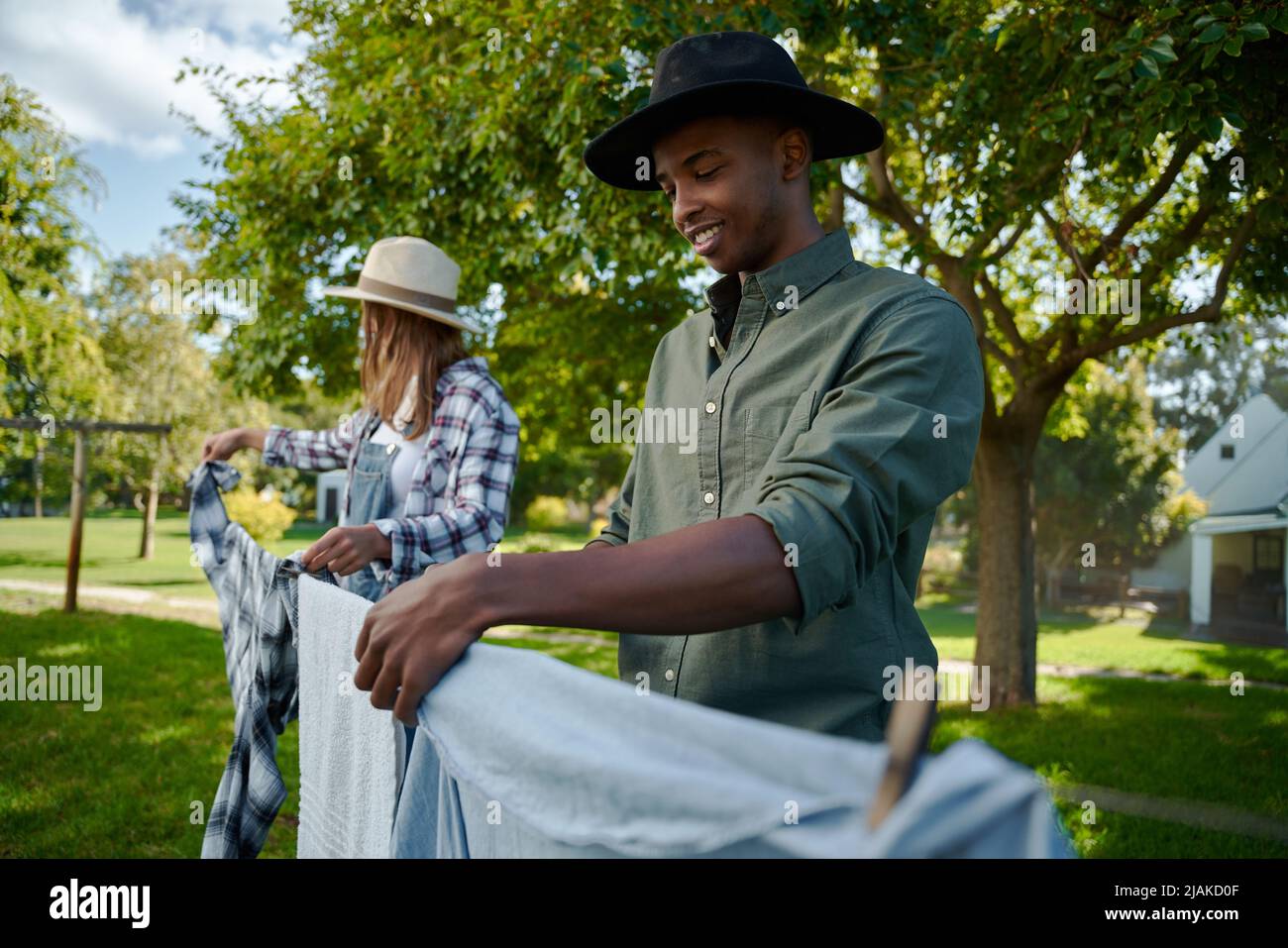 Mixed race male and female farmers hanging out washing on laundry line Stock Photo