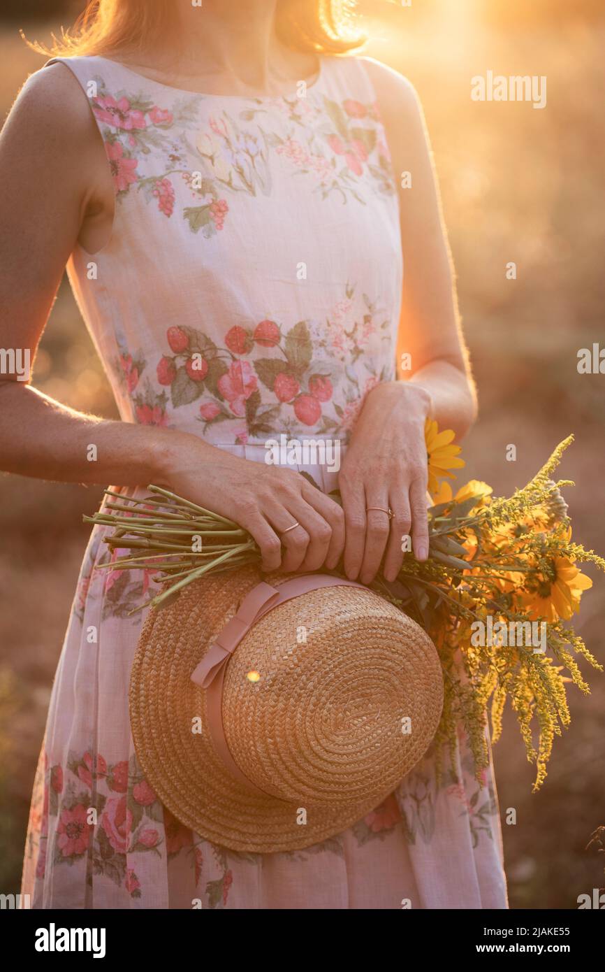 girl in a field at sunset with a hat and a bouquet of wildflowers Stock ...