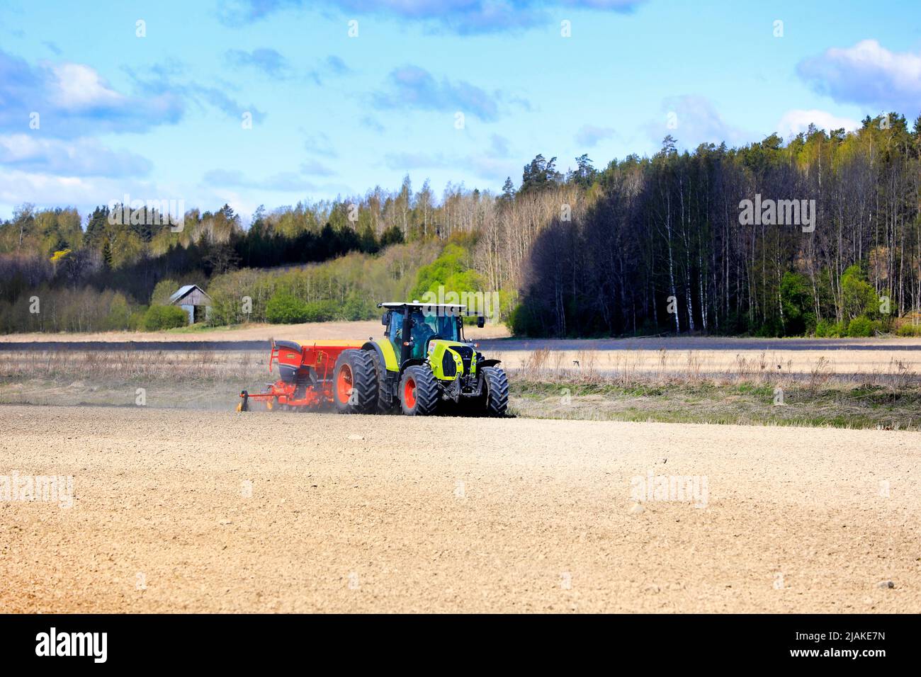 Farmer working with Claas Arion 650 tractor and Vaderstad Rapid 300C seed drill in field on a sunny day of spring. Salo, Finland. May 15, 2022. Stock Photo