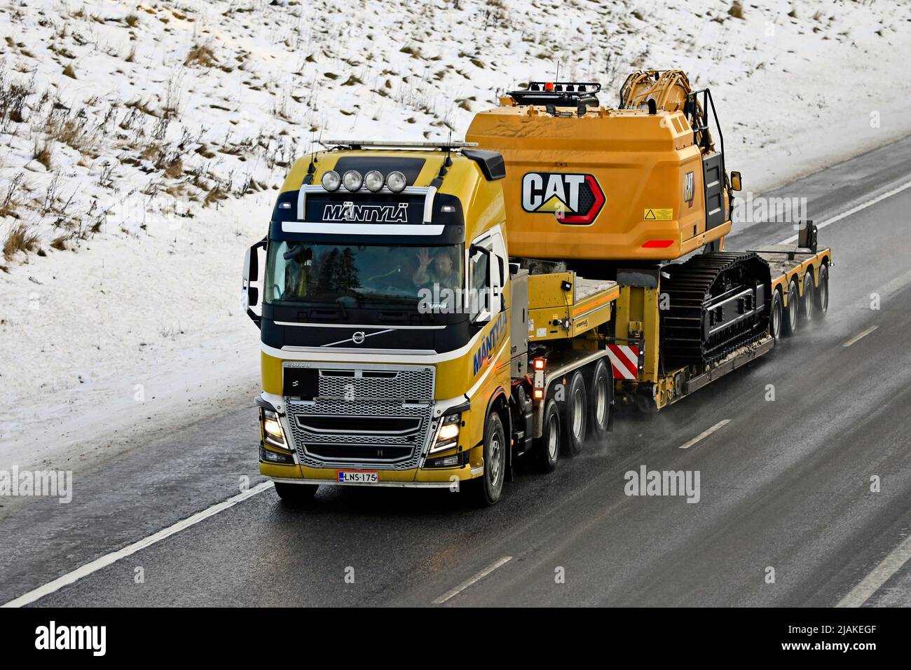 Yellow Volvo FH16 truck Mäntylä E&E hauls CAT 352 large hydraulic excavator on gooseneck trailer on motorway in winter. Salo, Finland. Dec 31, 2021. Stock Photo